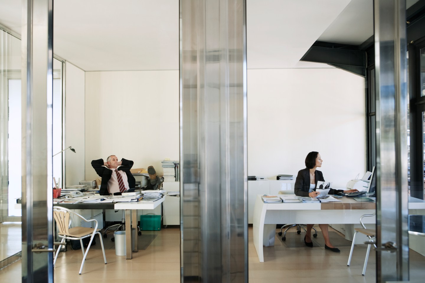 Businessman Relaxing as Businesswoman Works