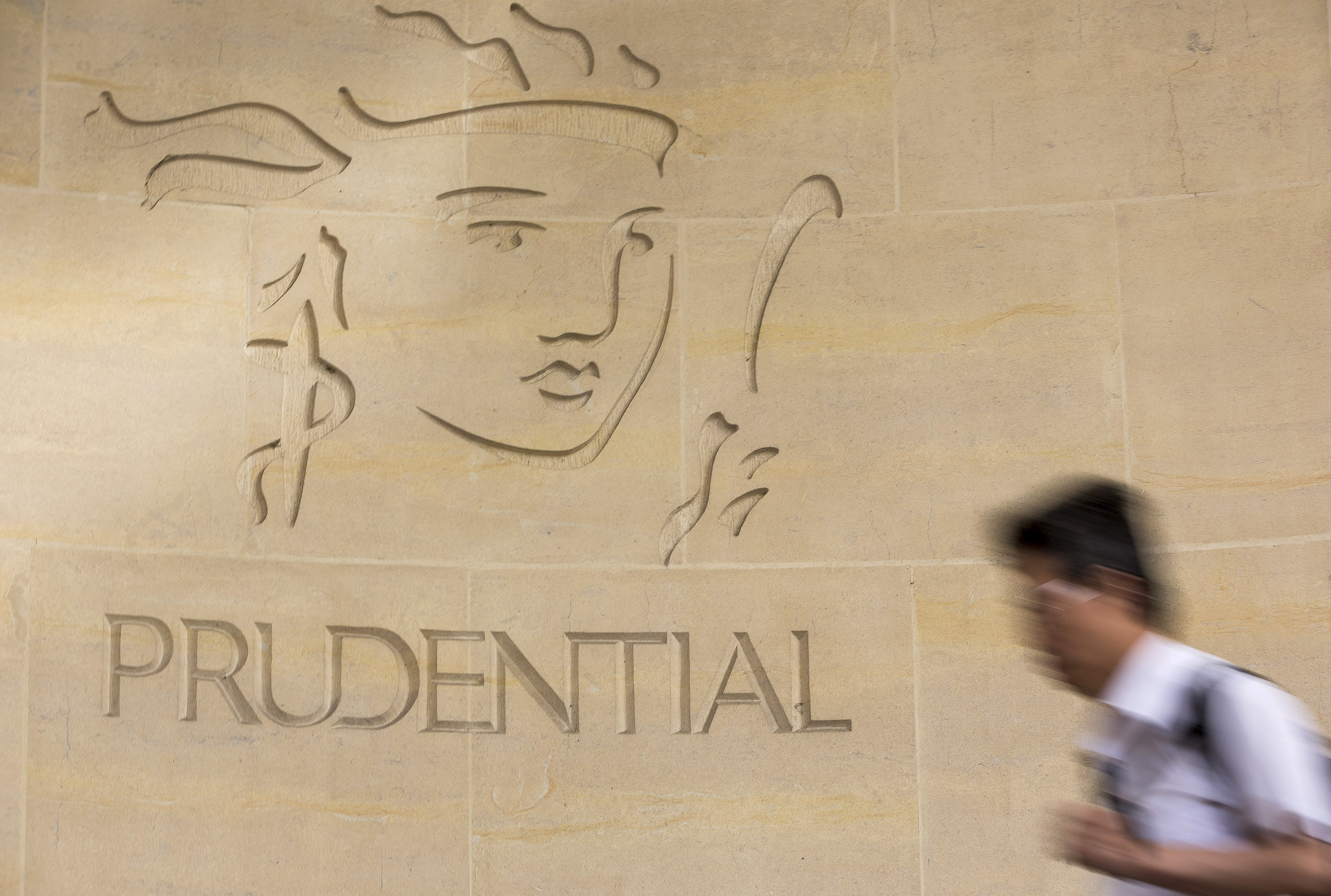 A pedestrian passes a logo outside Prudential Plc's headquarters in London, U.K., on Monday, Aug. 12, 2013.