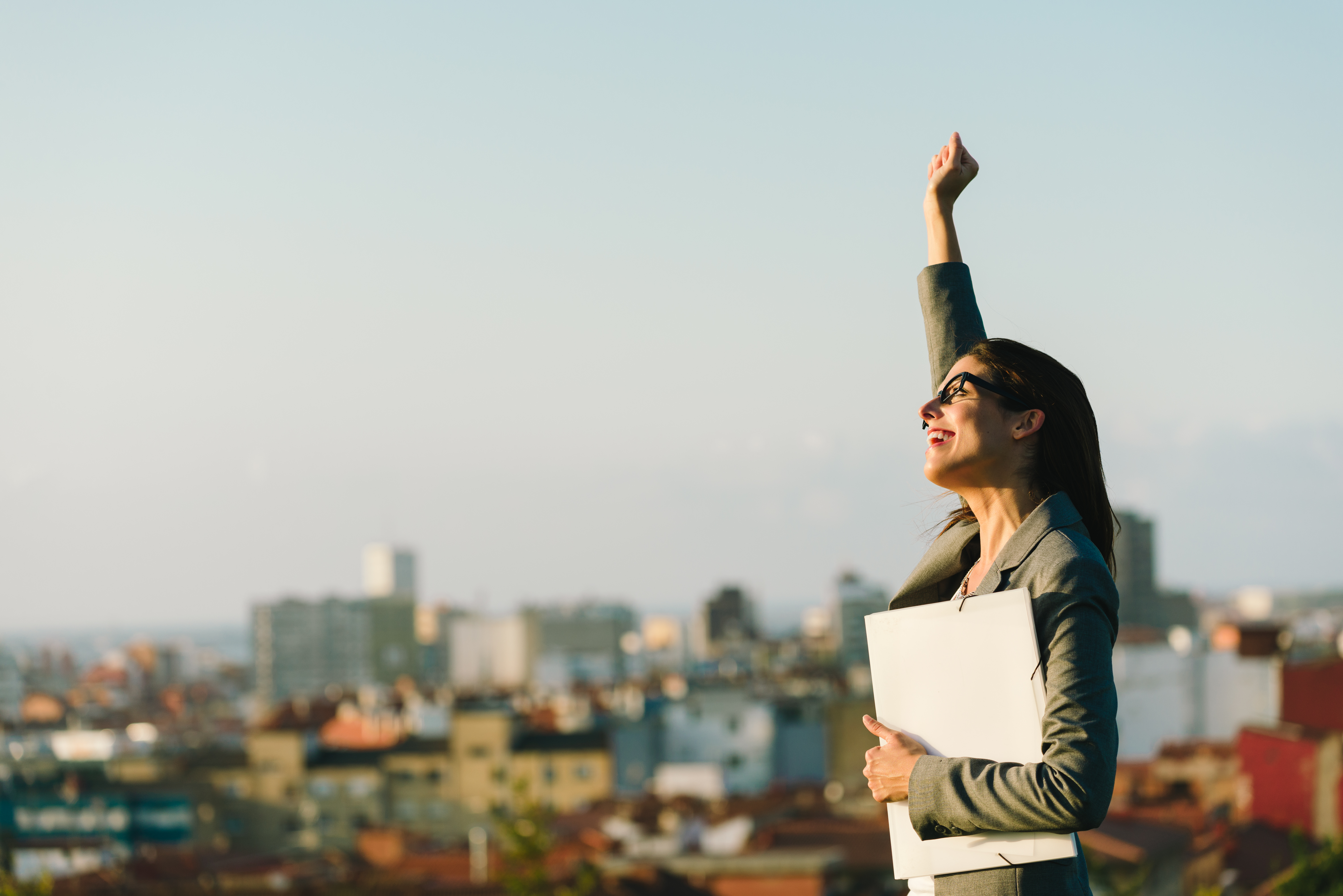 Successful young city business woman raising arm