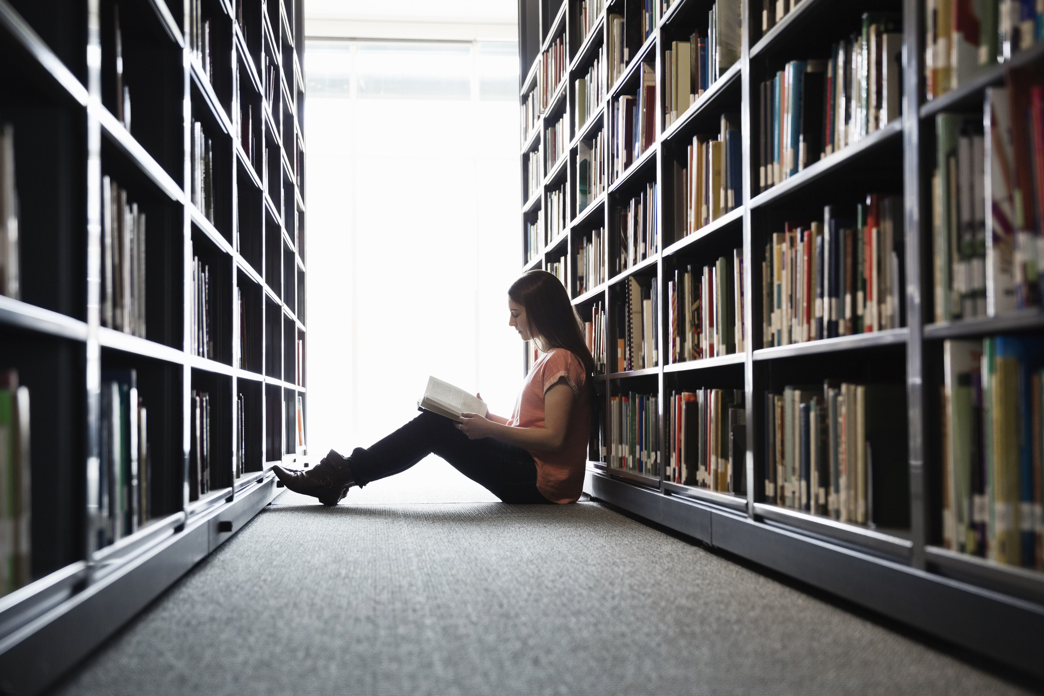 Female student sitting on library floor at college campus