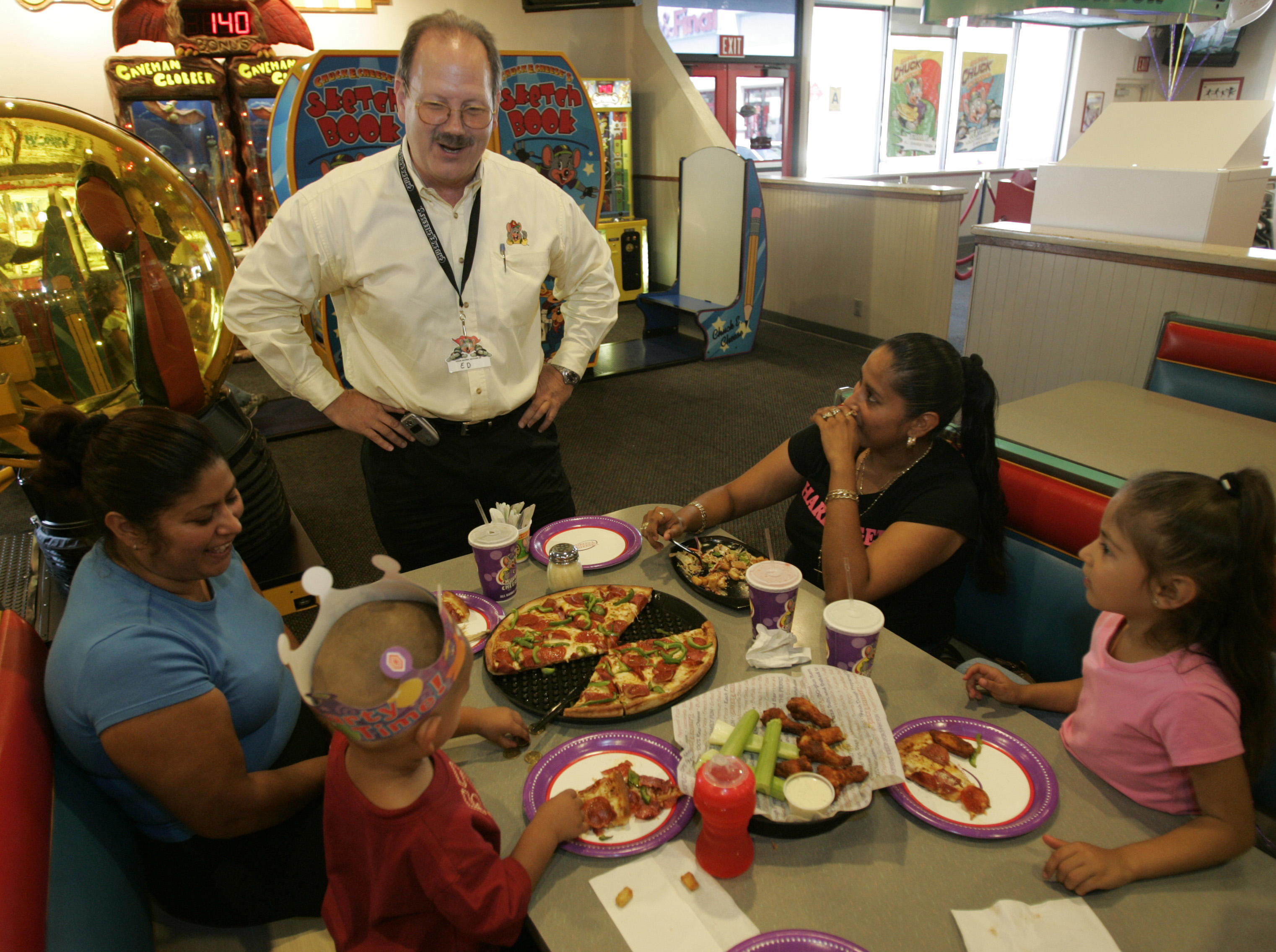 Ed Porter, Area Director for Chuck E. Cheese, chats with a family having a birthday party. This sto