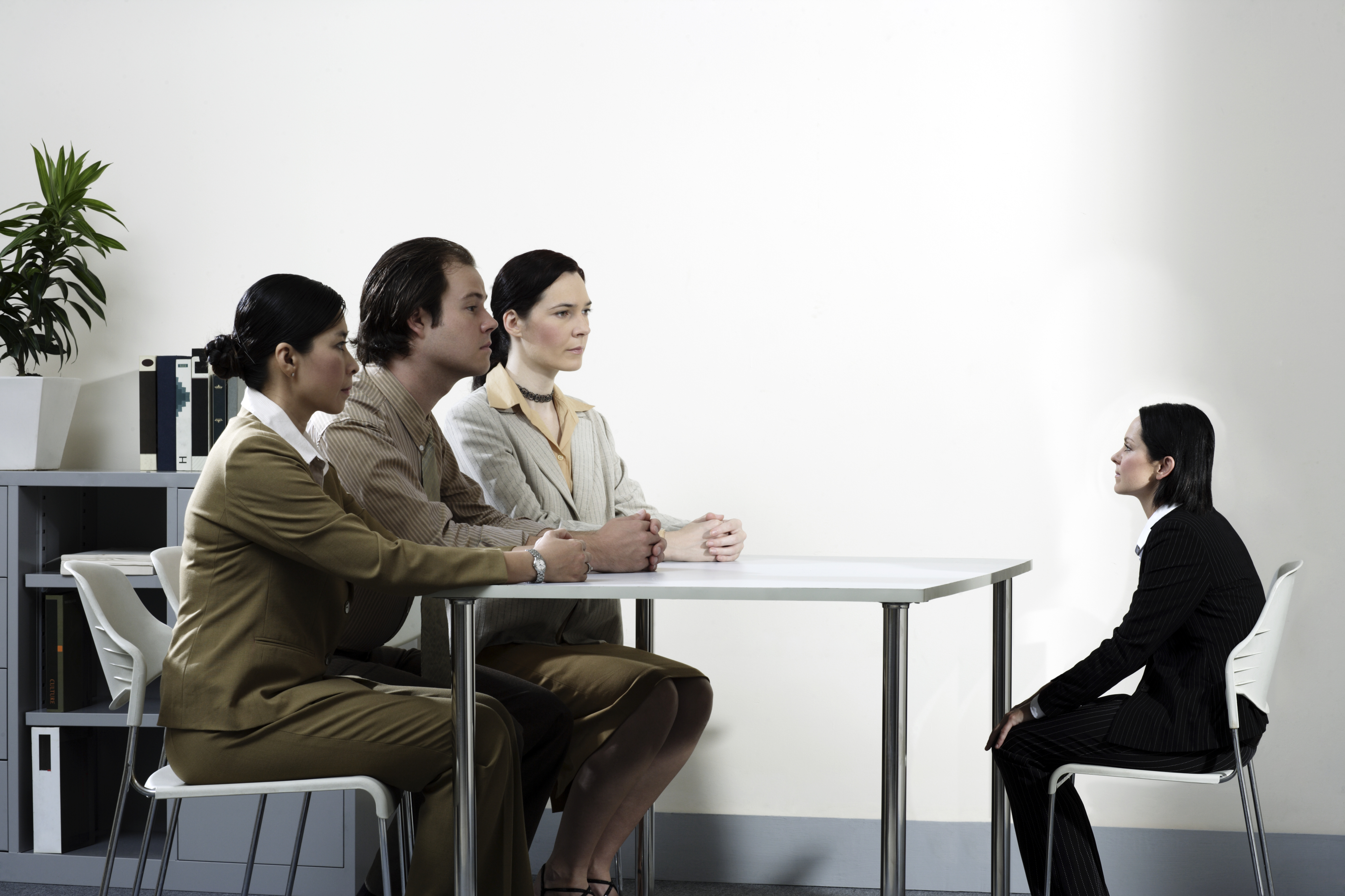 Three giant business people interviewing small female colleague (Digital Composite)