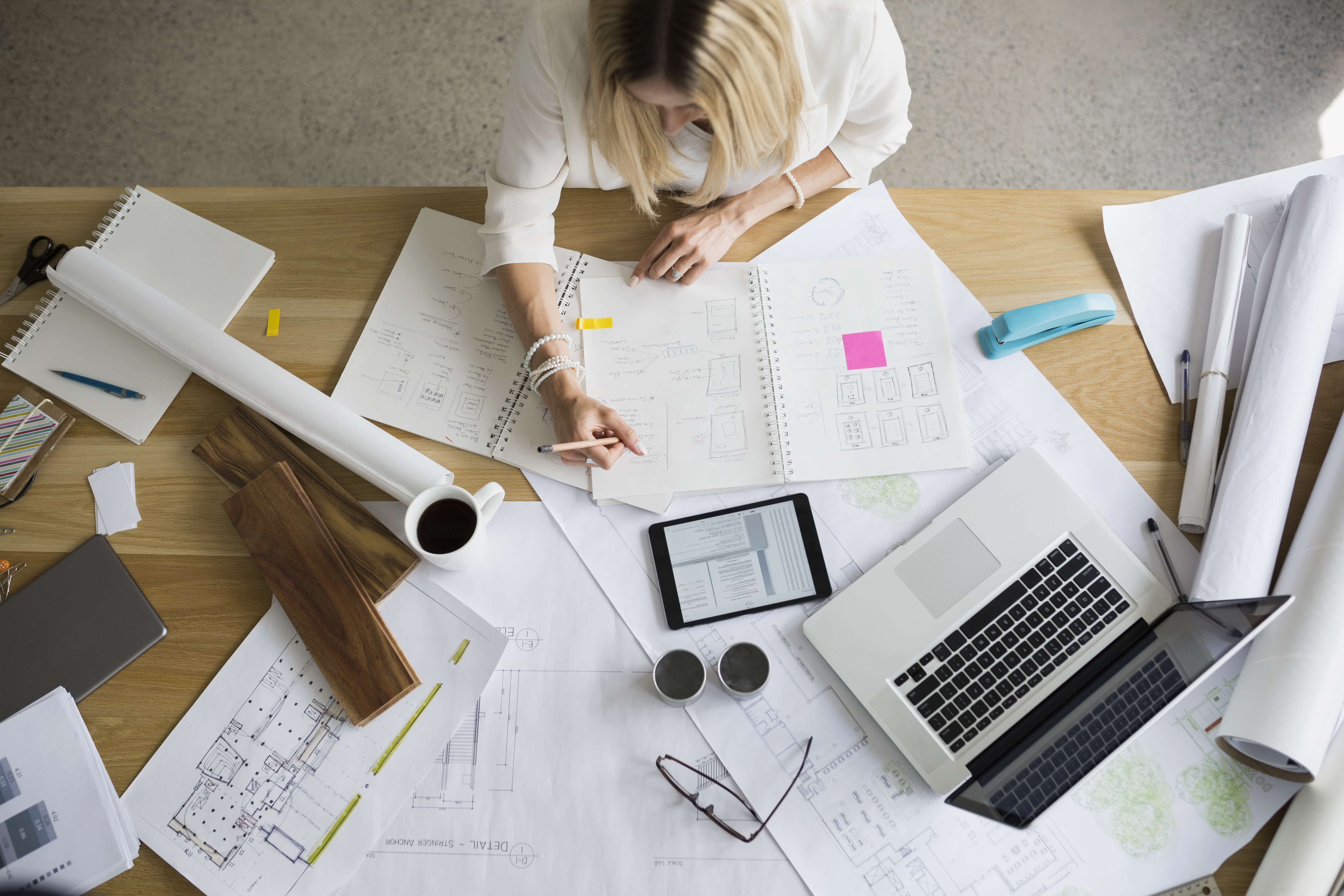 Overhead view architect drafting blueprints at table