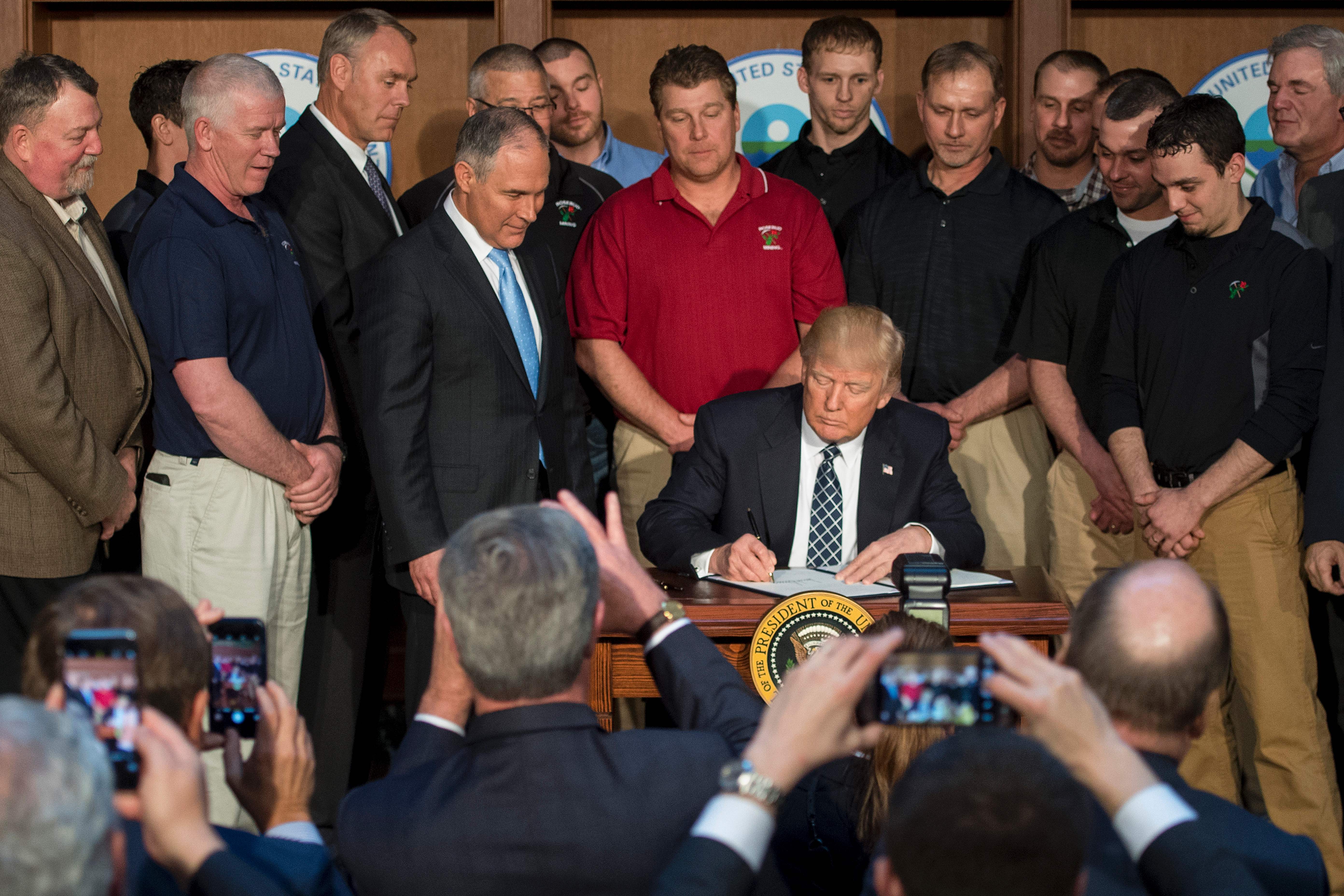 Surrounded by miners from Rosebud Mining, US President Donald Trump (C) signs he Energy Independence Executive Order at the Environmental Protection Agency (EPA) Headquarters in Washington, DC, March 28, 2017.
President Donald Trump claimed an end to the "war on coal" Tuesday, as he moved to roll back climate protections enacted by predecessor Barack Obama. / AFP PHOTO / JIM WATSON (Photo credit should read JIM WATSON/AFP/Getty Images)