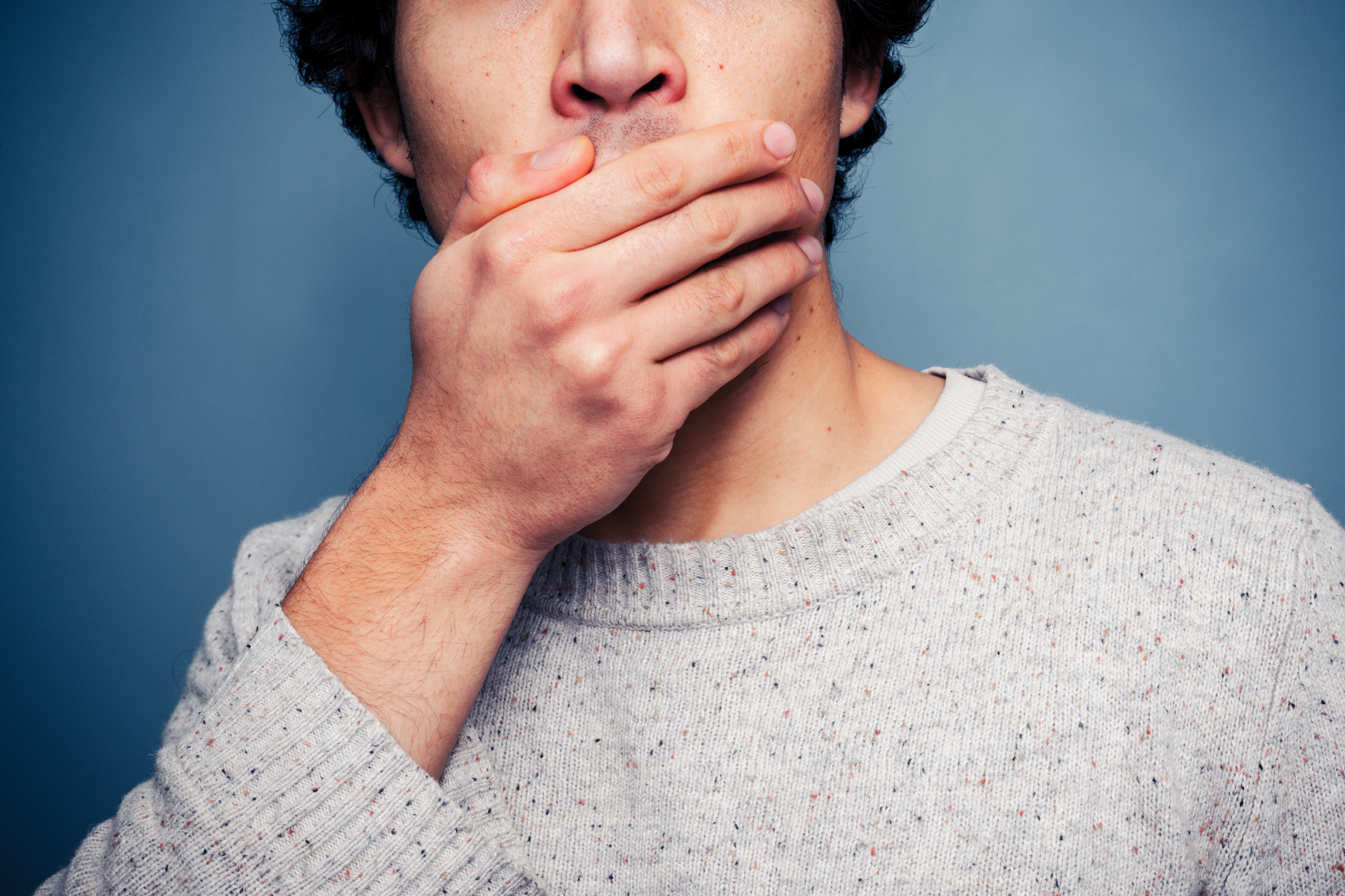 Shocked young man covering his mouth