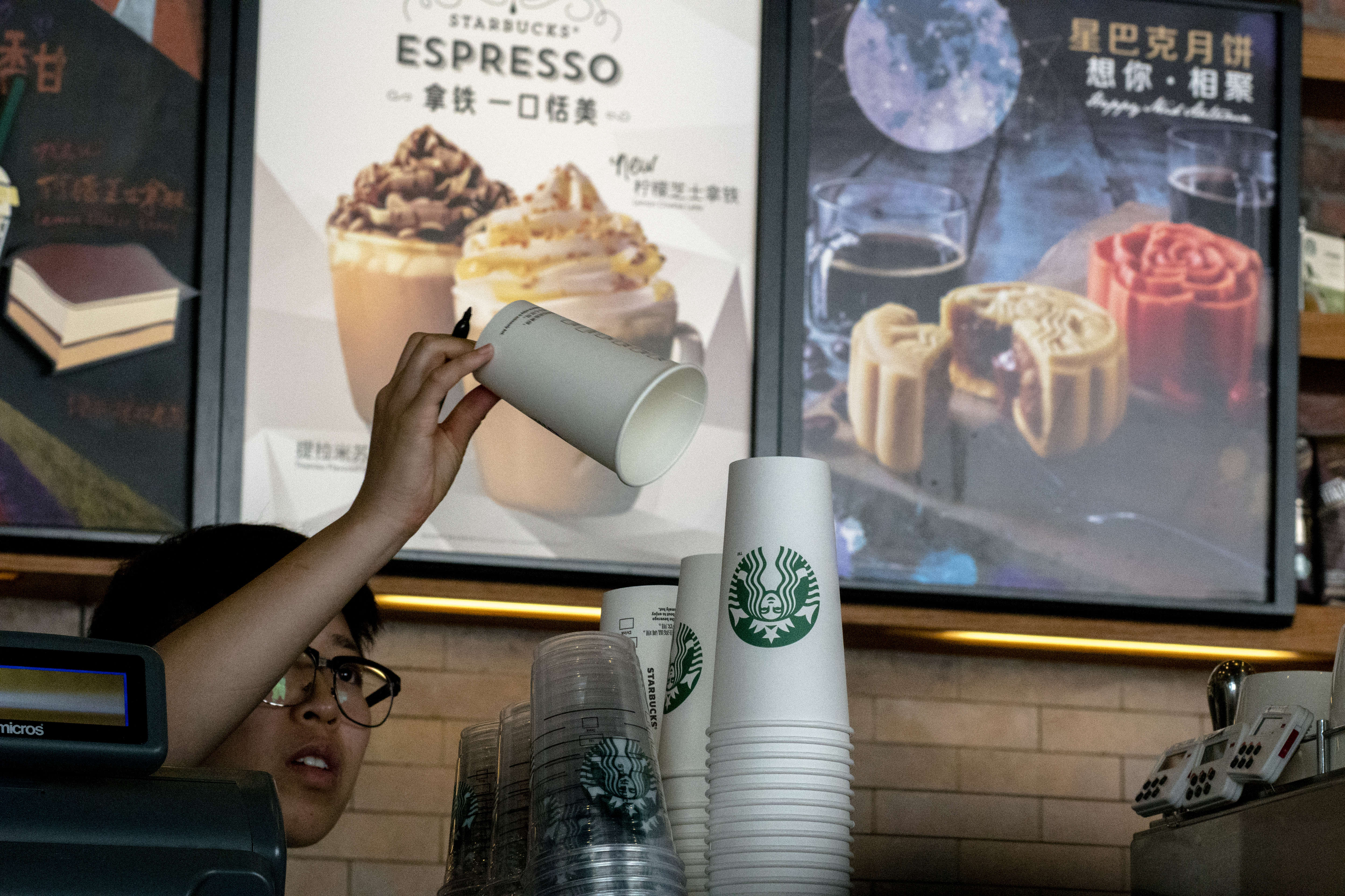 Barista prepares a paper cup in a Starbucks coffee shop.