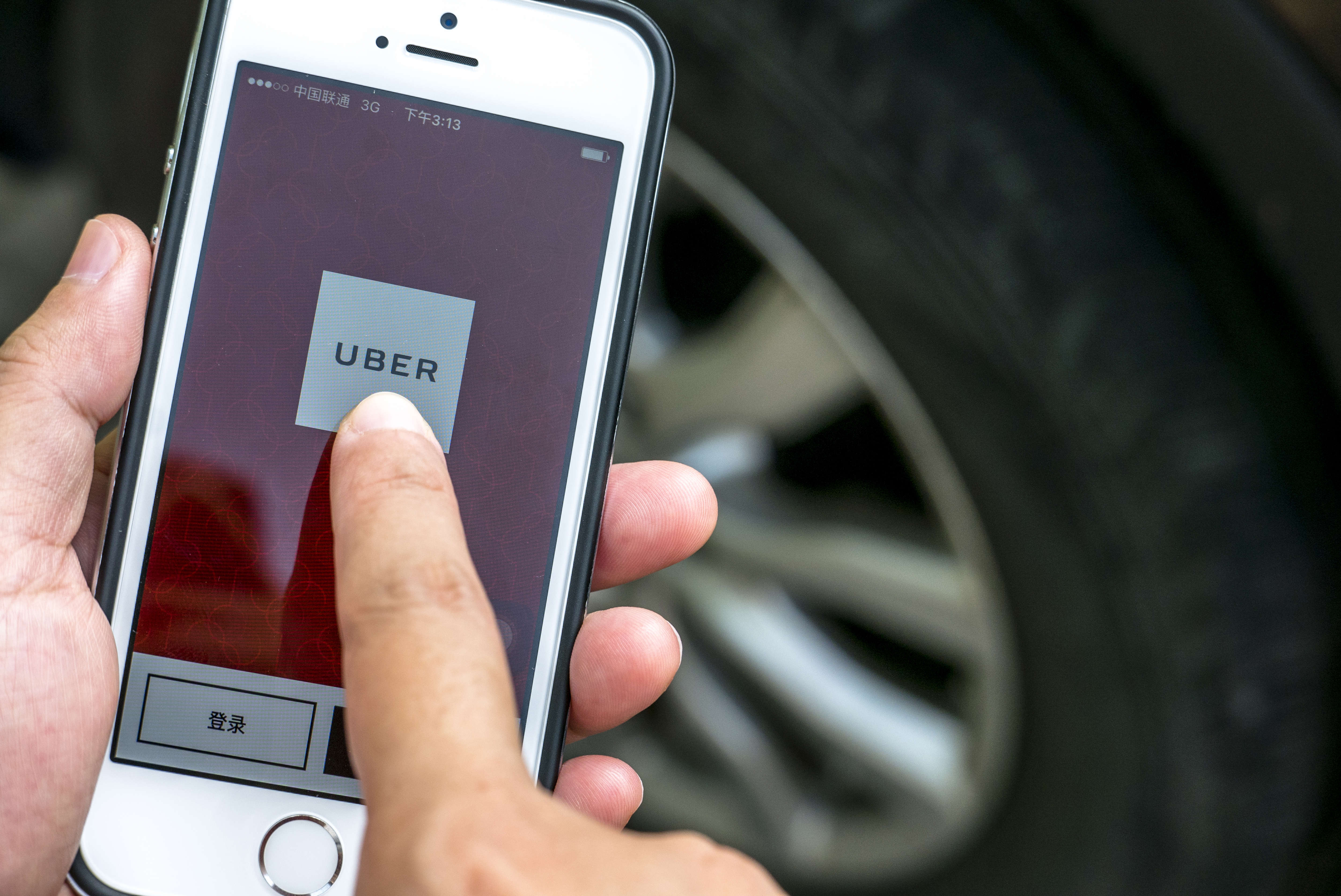 Hand holding a smart phone with Uber App. Uber is selling