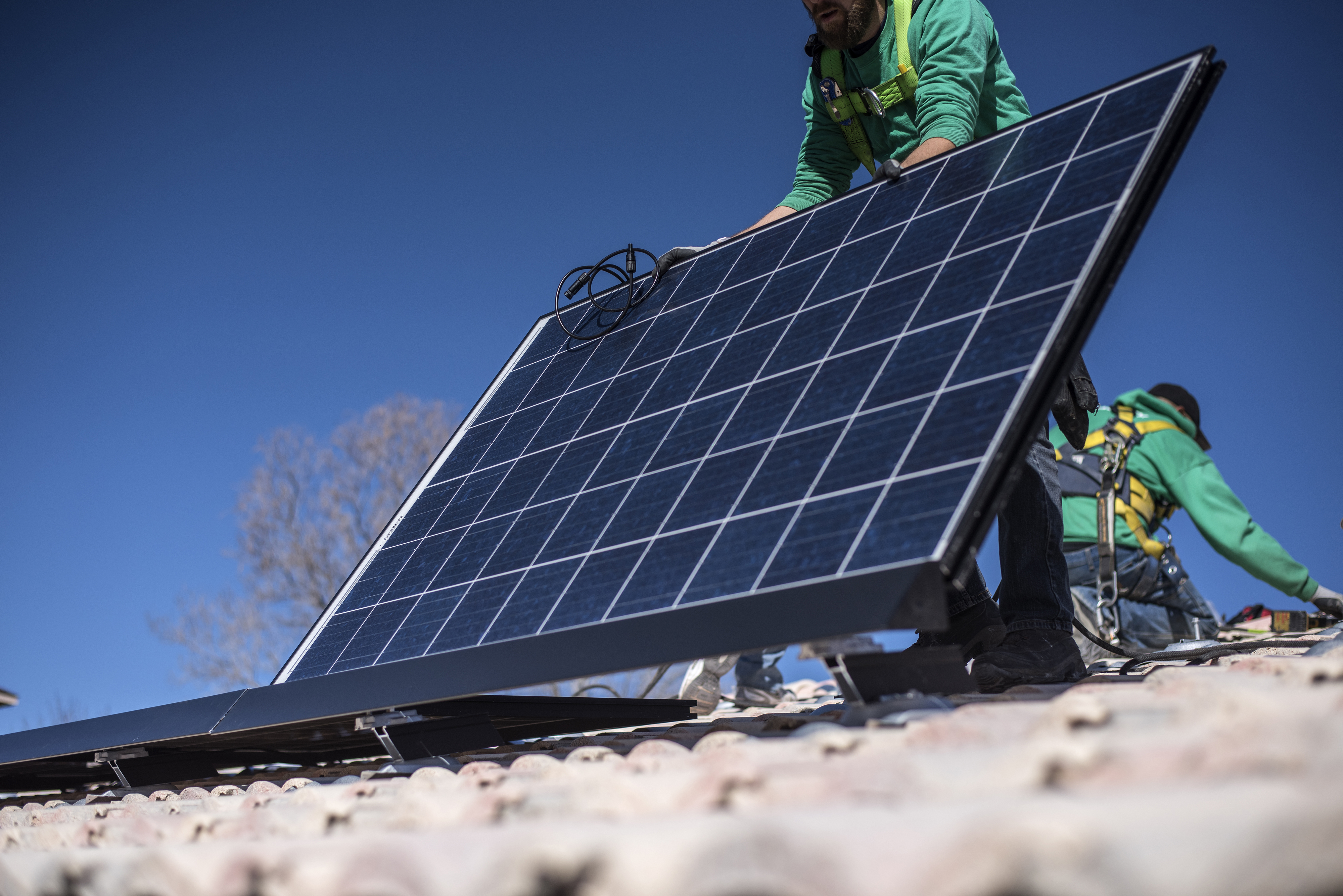 A worker lays down a solar panel on a rooftop during a SolarCity Corp. residential installation in Albuquerque, New Mexico, U.S., on Monday, Feb. 8, 2016.