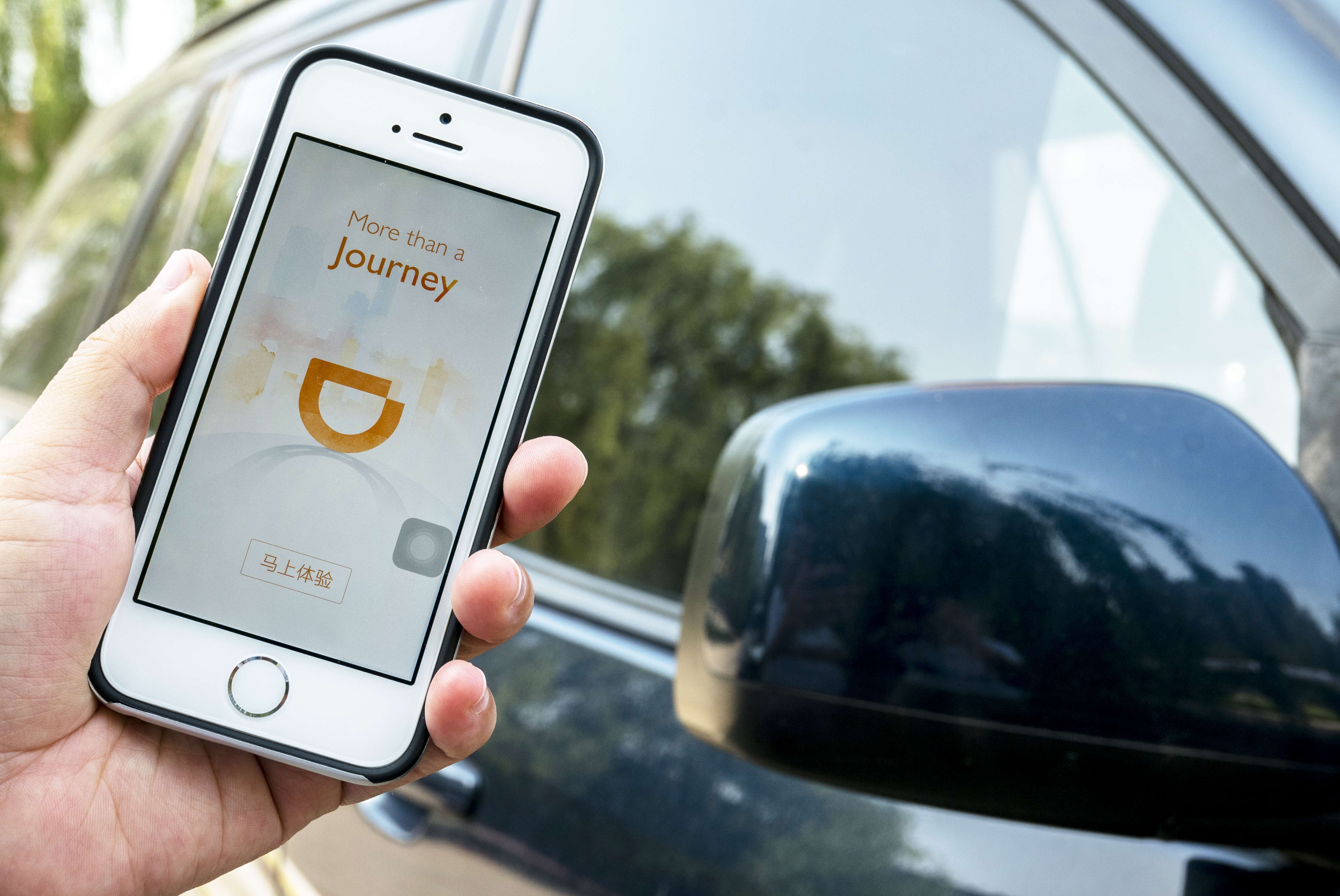 Hand holding a smart phone with an App of Didi Chuxing.