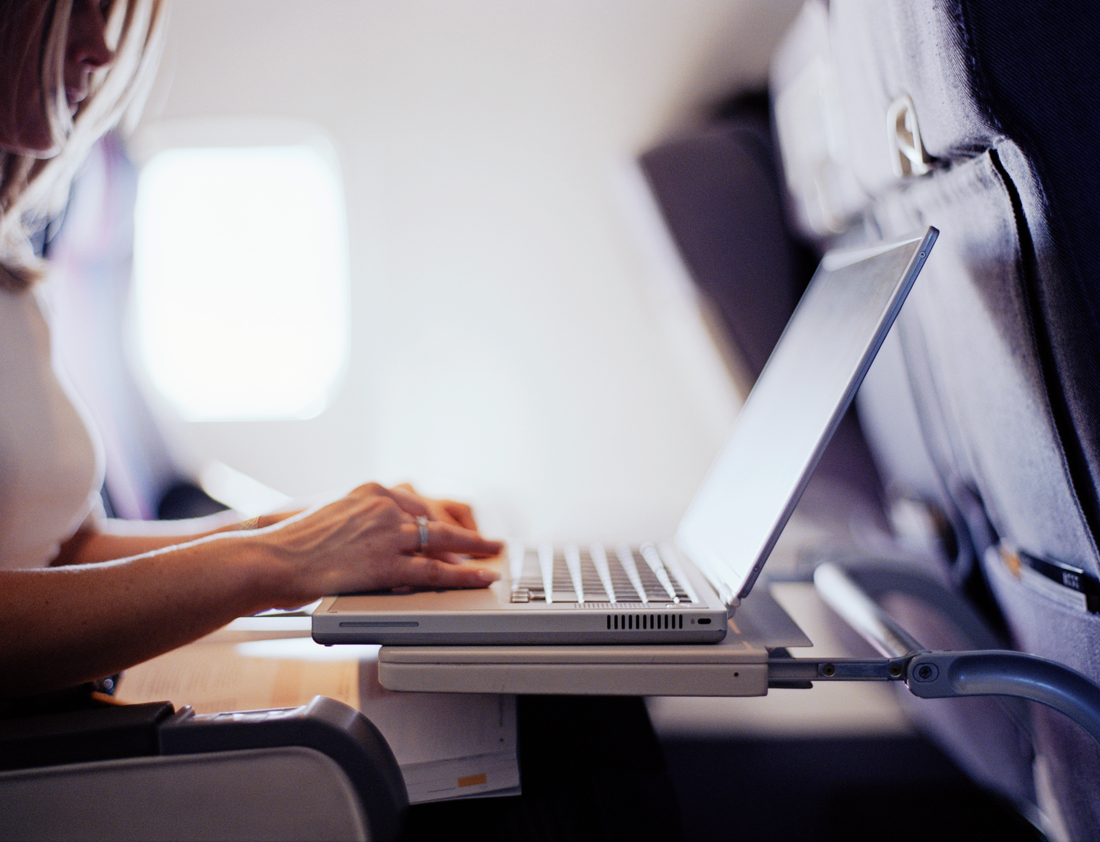 Woman typing on laptop computer in commercial airplane