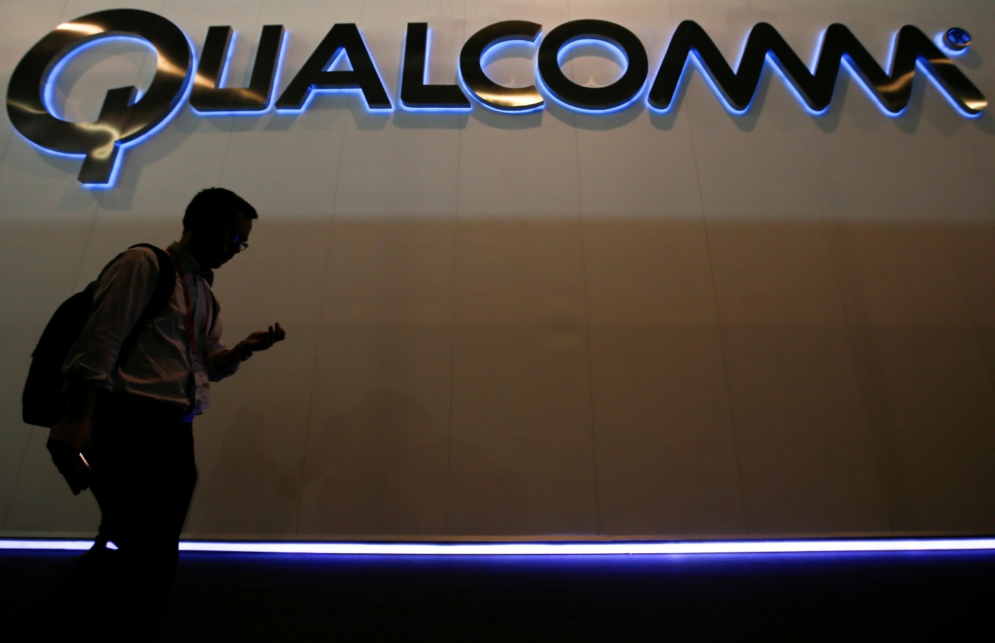 A man walks past Qualcomm stand while attending during the Mobile World Congress in Barcelona