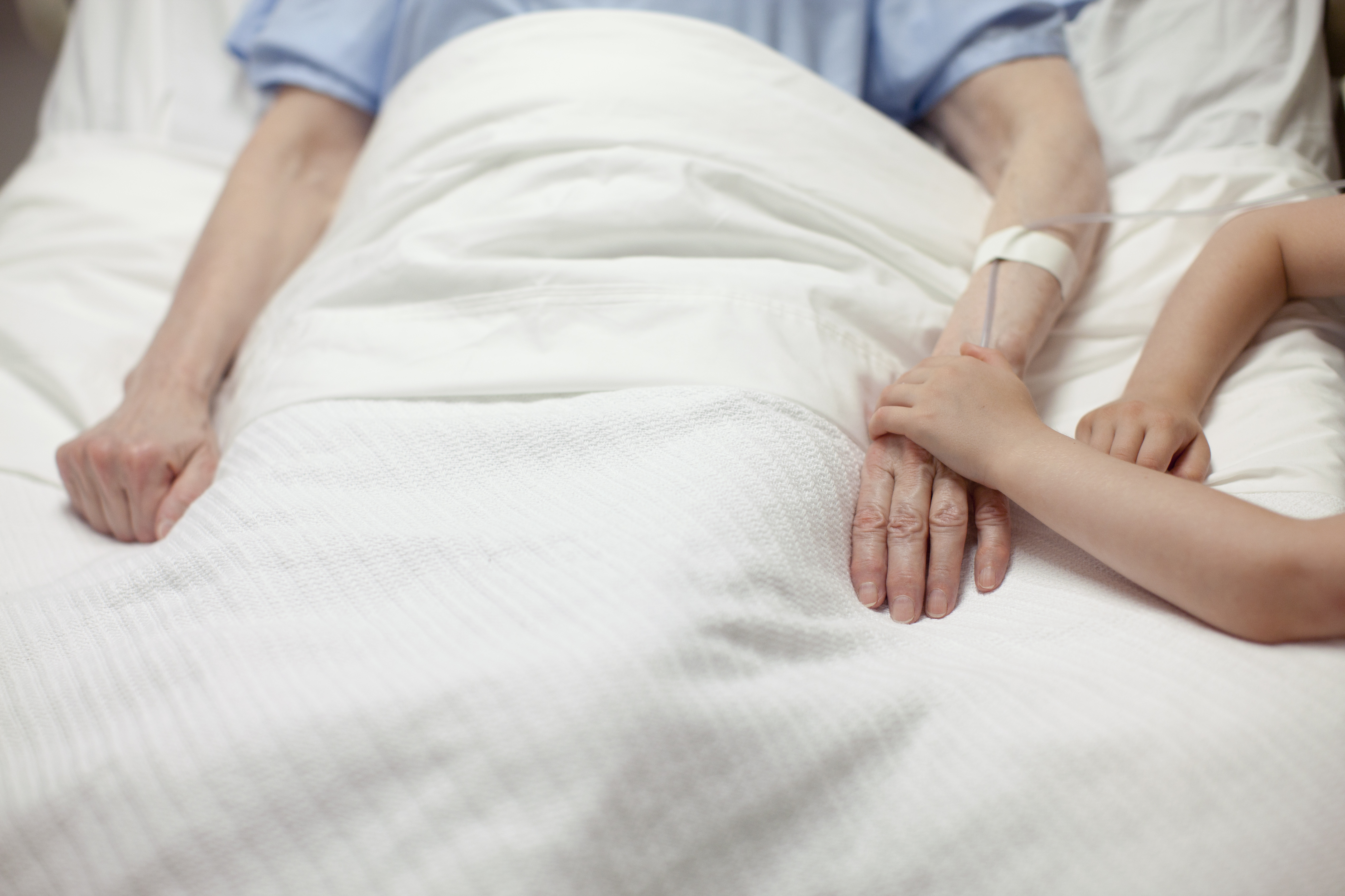 Young girl holding grandma's hand in hospital