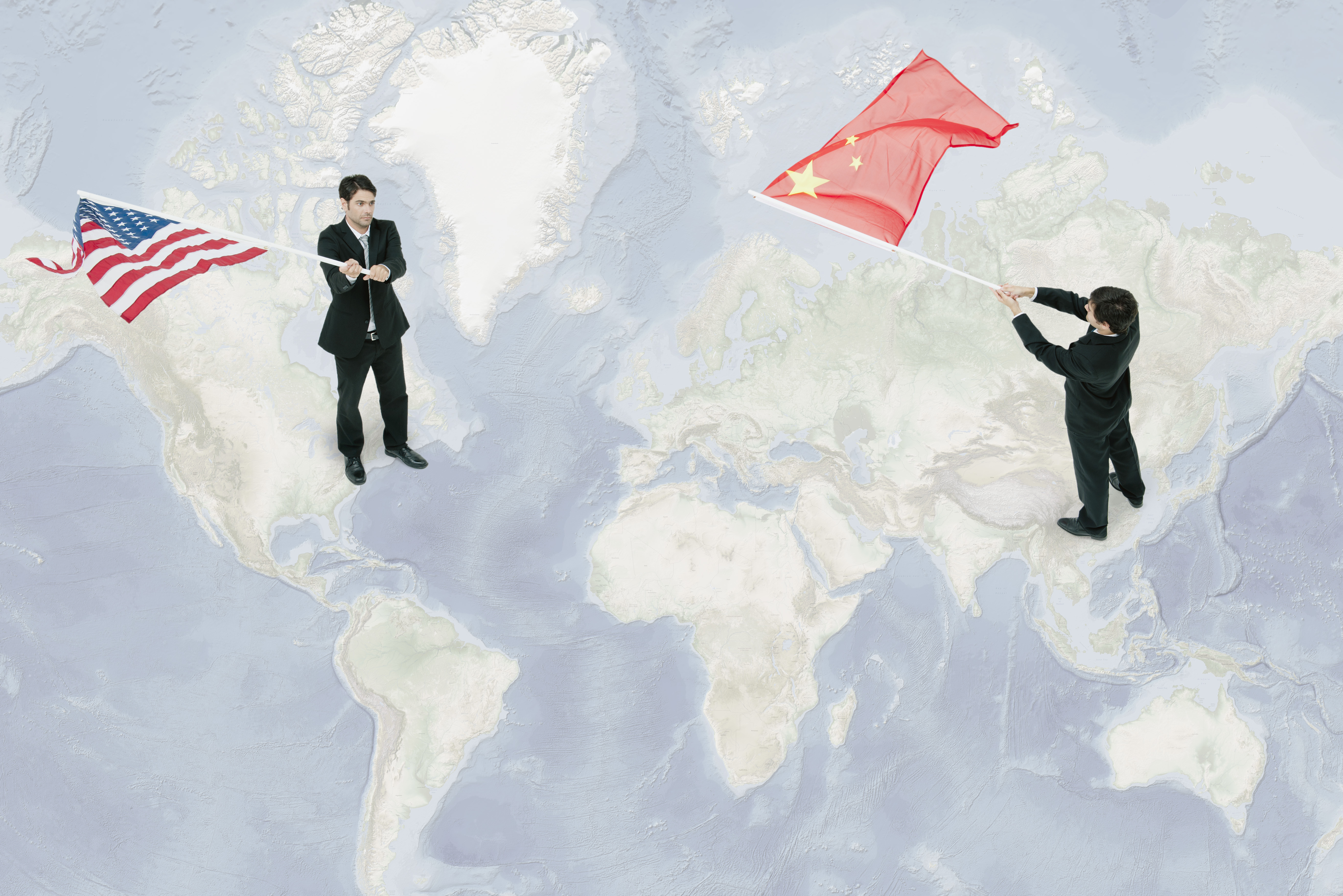 Businessmen standing on world map, waving American and Chinese flags