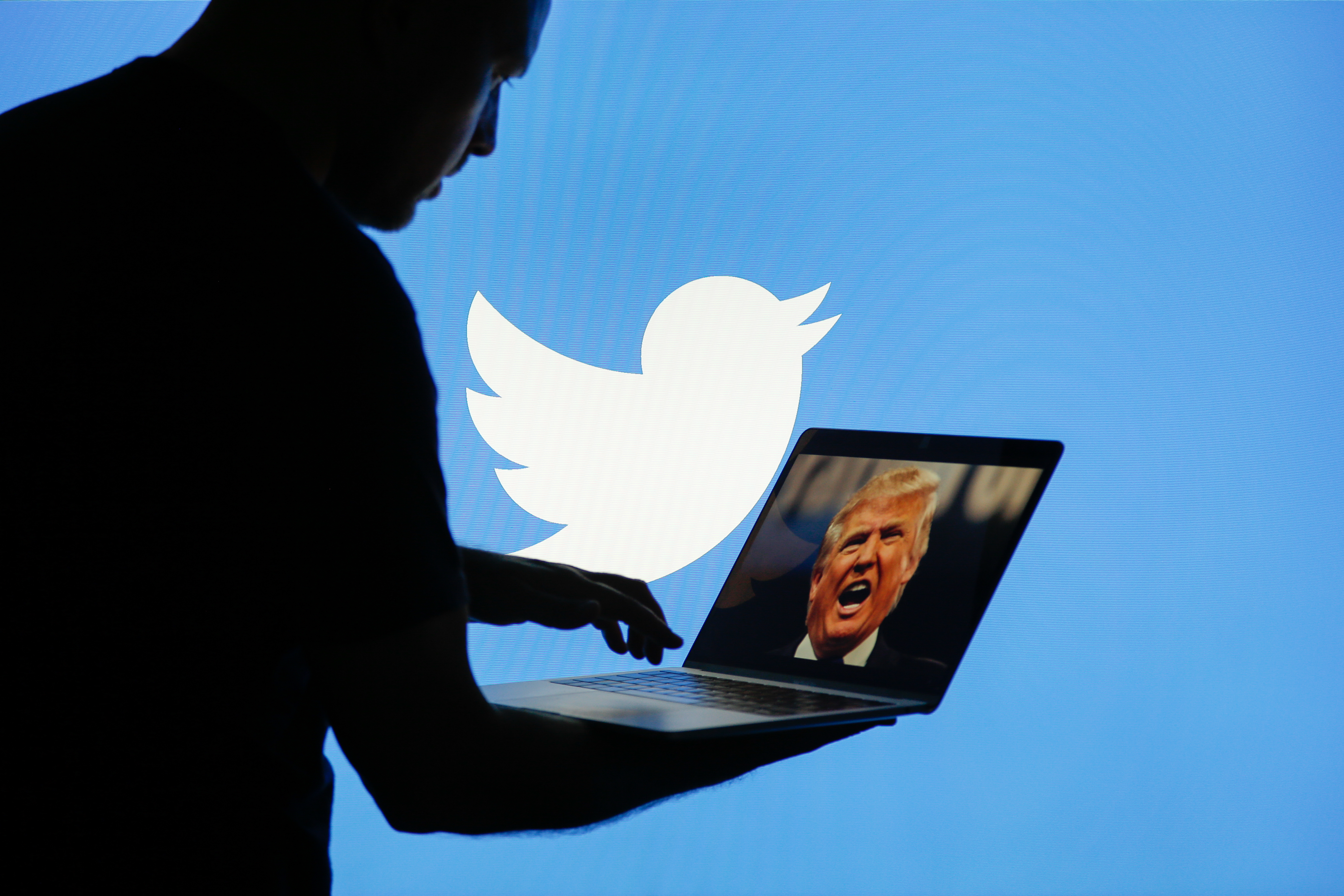 A man is seen with a laptop depicting an image of U.S. president Donald Trump with a Twitter logo displayed in the background in this photo illustration on 2 July, 2017.