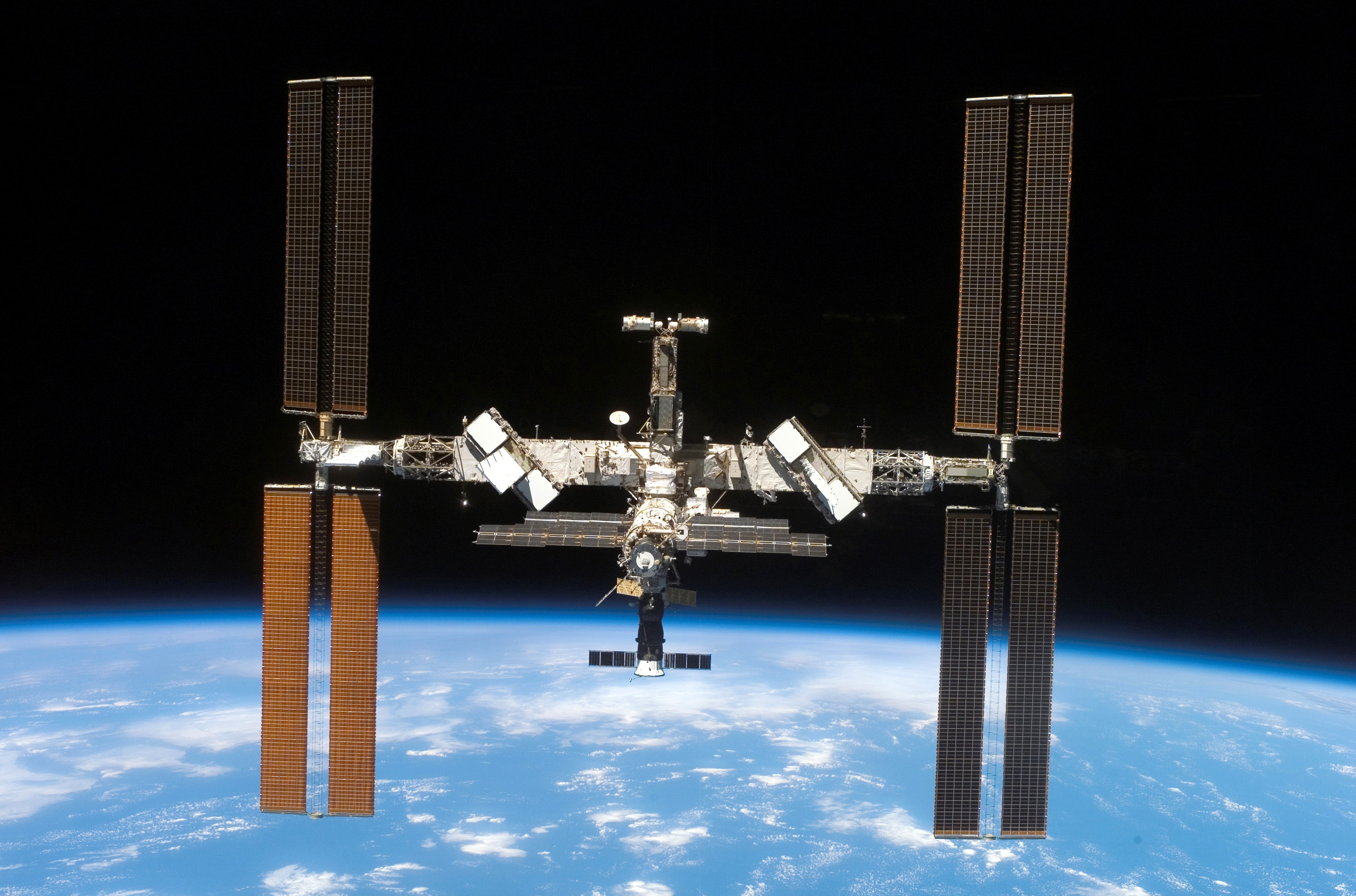 Backdropped by the blackness of space and Earths horizon, the International Space Station and Space Shuttle Atlantis move farther apart at the end of STS-117s mission, during which the shuttle and station crews concluded about eight days of cooperative wor