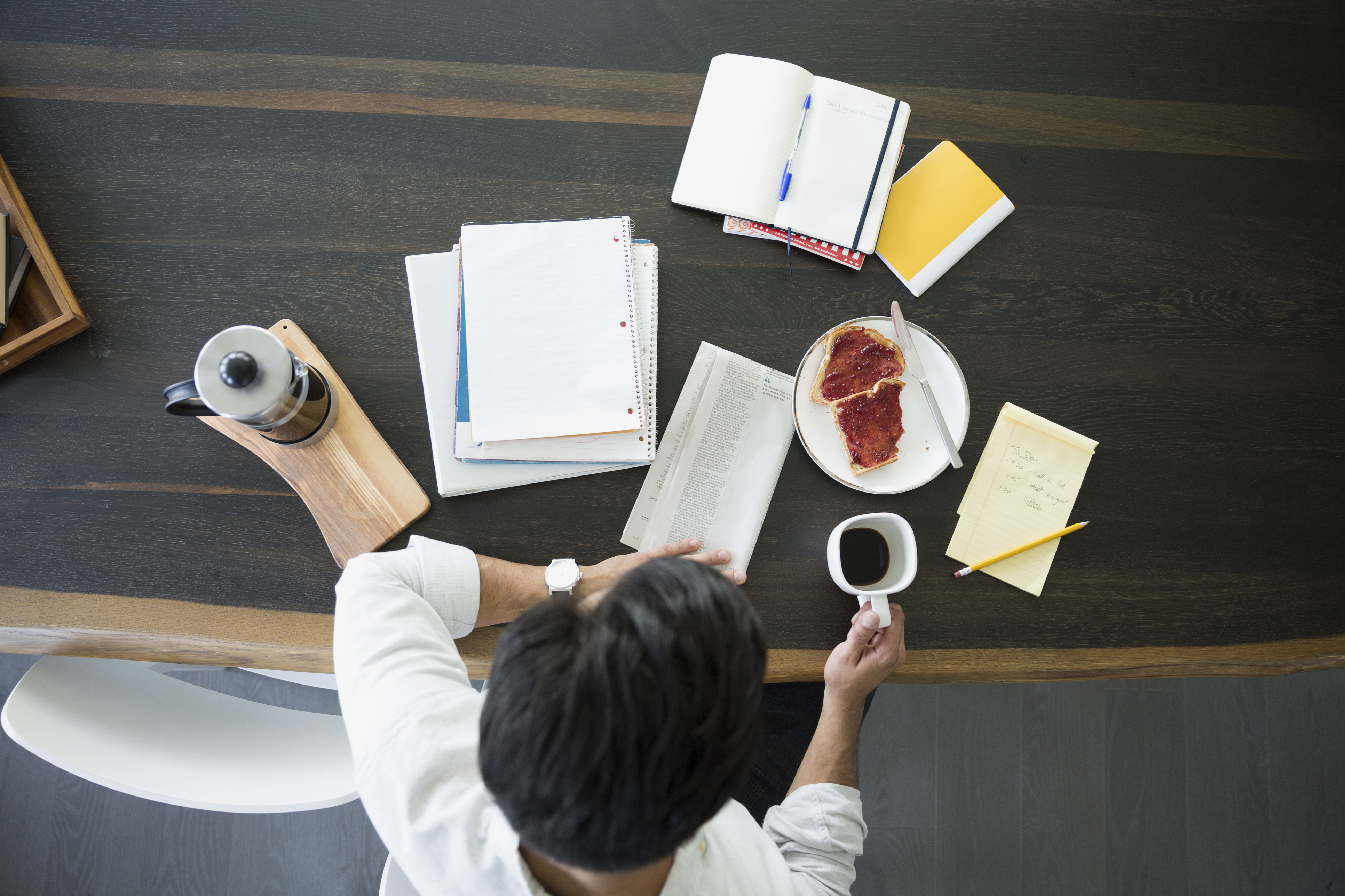 Overhead view of man with coffee newspaper table
