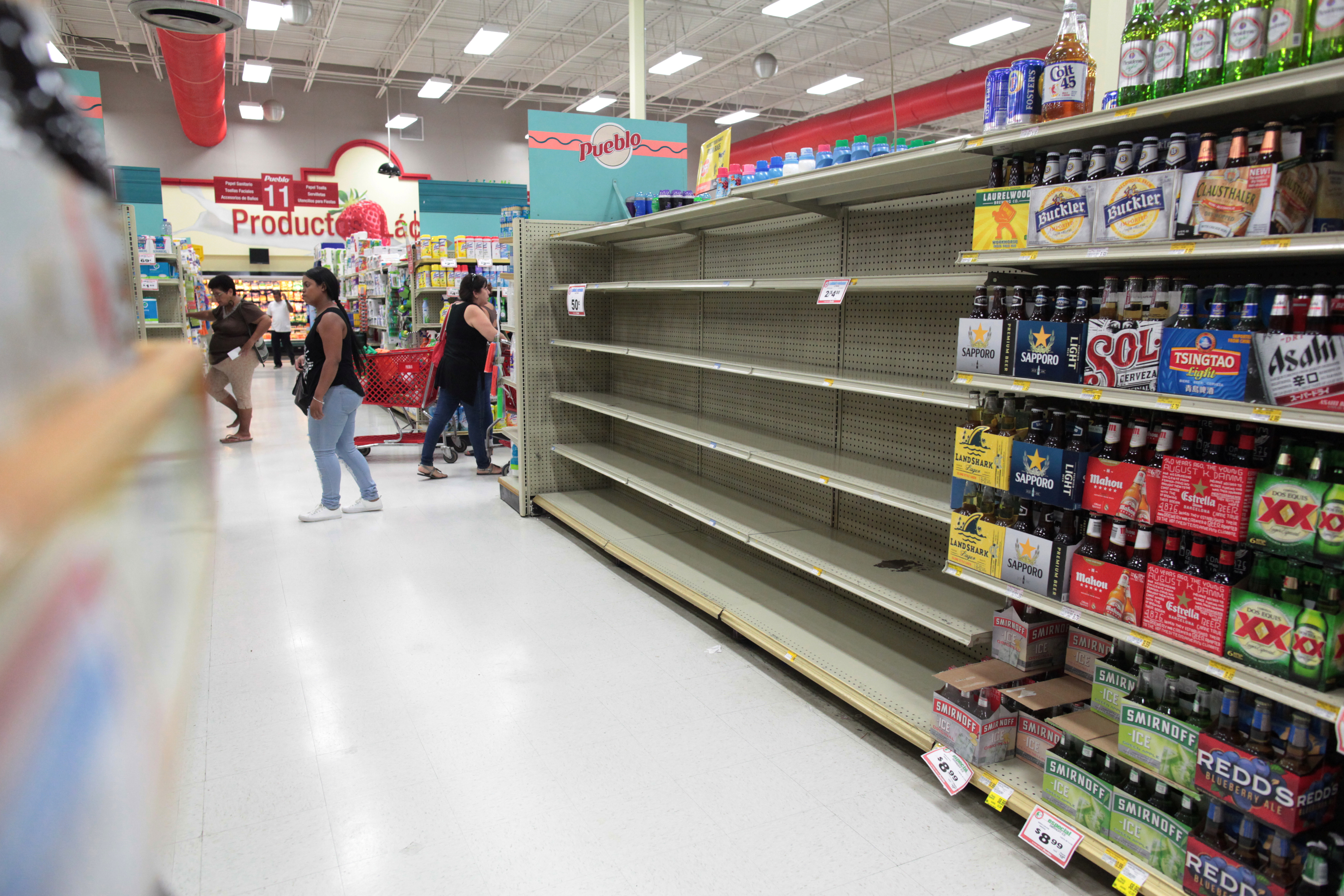 Customers walk near empty shelves that are normally filled with bottles of water after Puerto Rico Governor Ricardo Rossello declared a state of emergency in preparation for Hurricane Irma, in San Juan