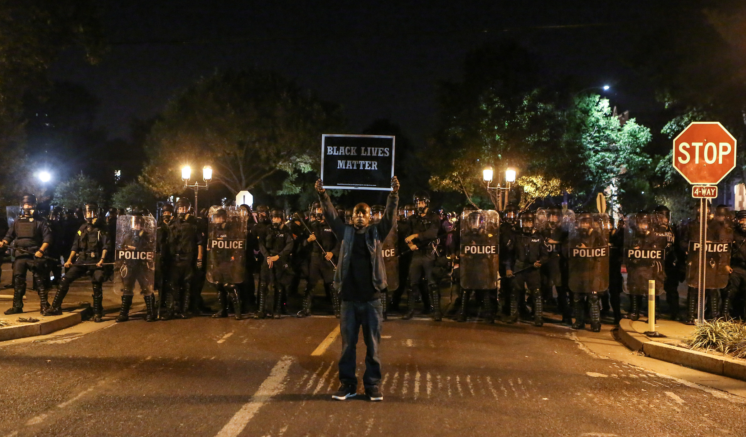 A Black Lives Matter protester stands in front of St. Louis Police Department officers equipped with riot gear in St. Louis