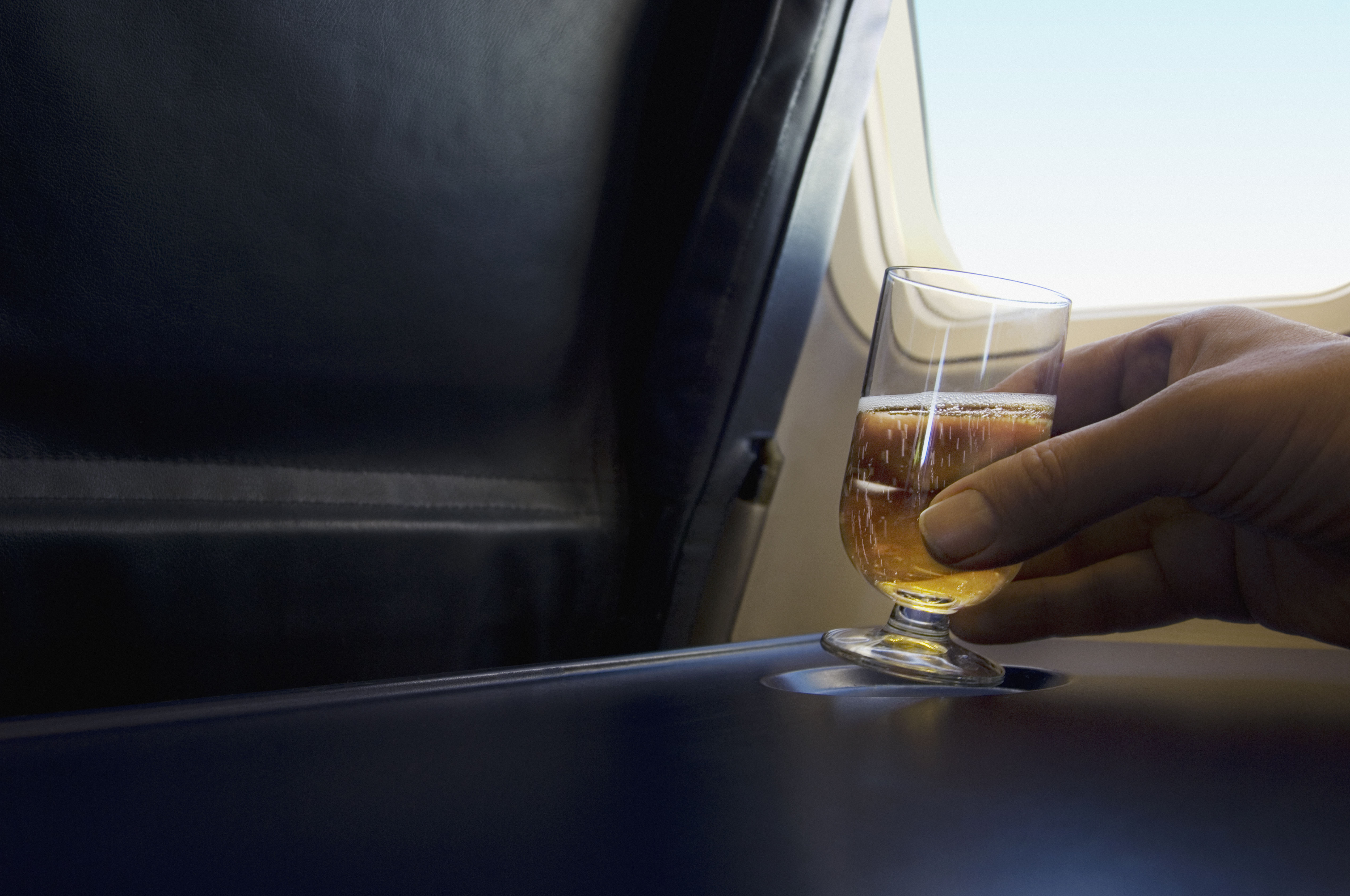 Man holding a glass of champagne on airplane