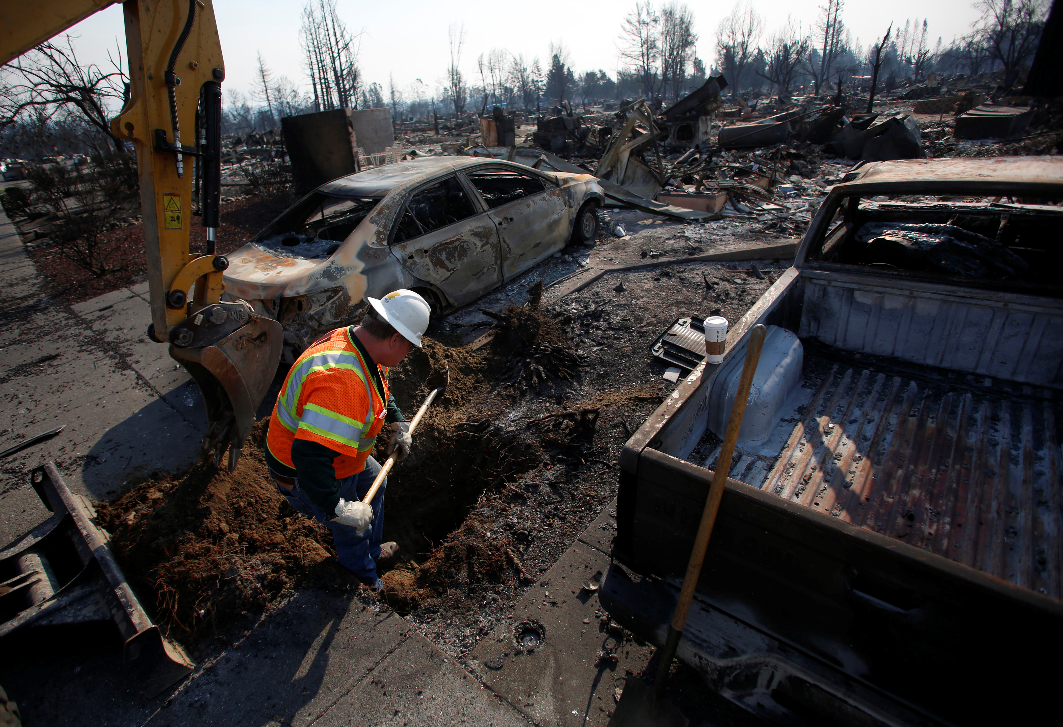 An employee of Pacific Gas & Electric (PG&E) digs to find an electrical transformer in a destroyed neighborhood after a wildfire tore through Santa Rosa, California
