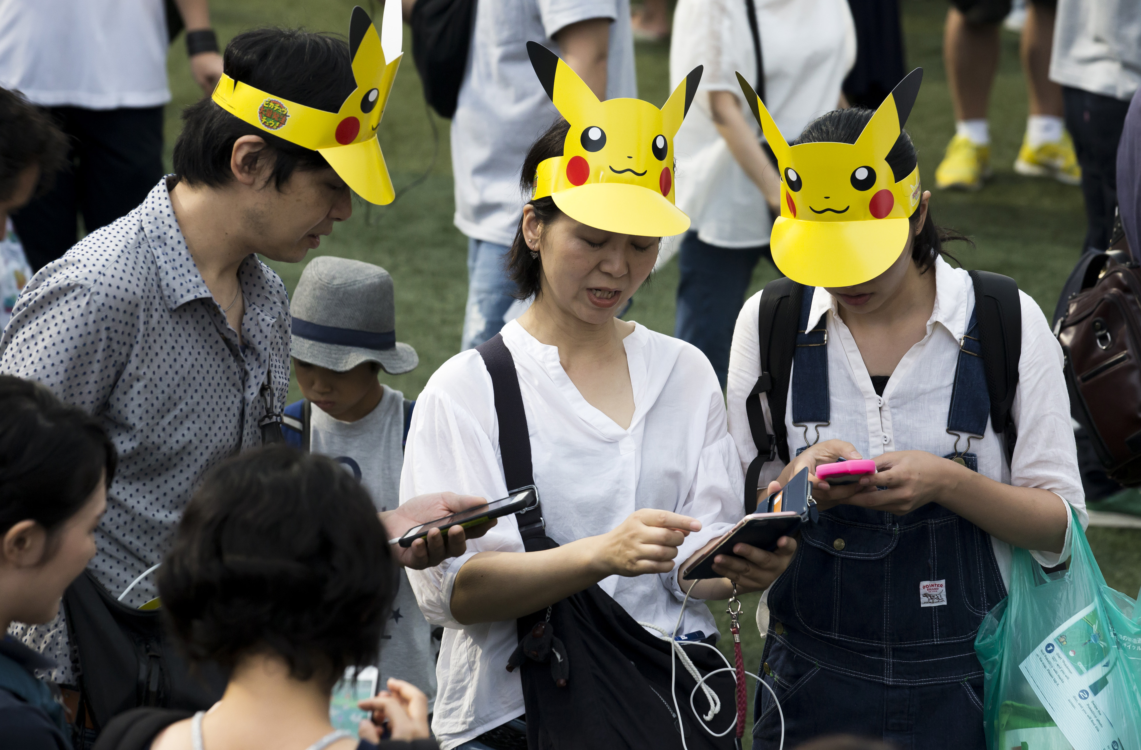 People wearing Pikachu caps play Pokemon Go in Japan