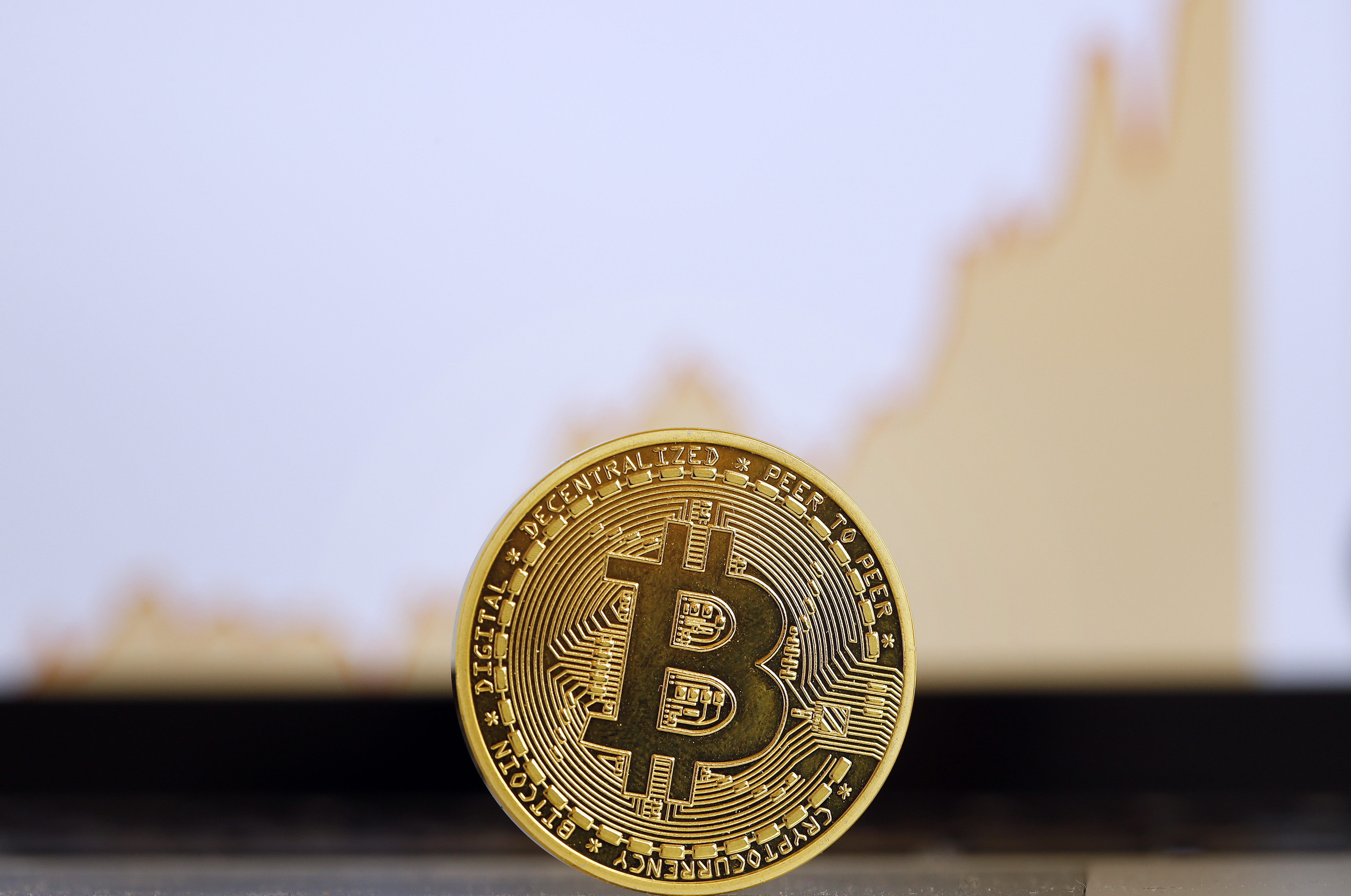The digital cryptocurrency Bitcoin is visually displayed as a physical coin in front of a price chart is displayed on November 30, 2017 in Paris, France.