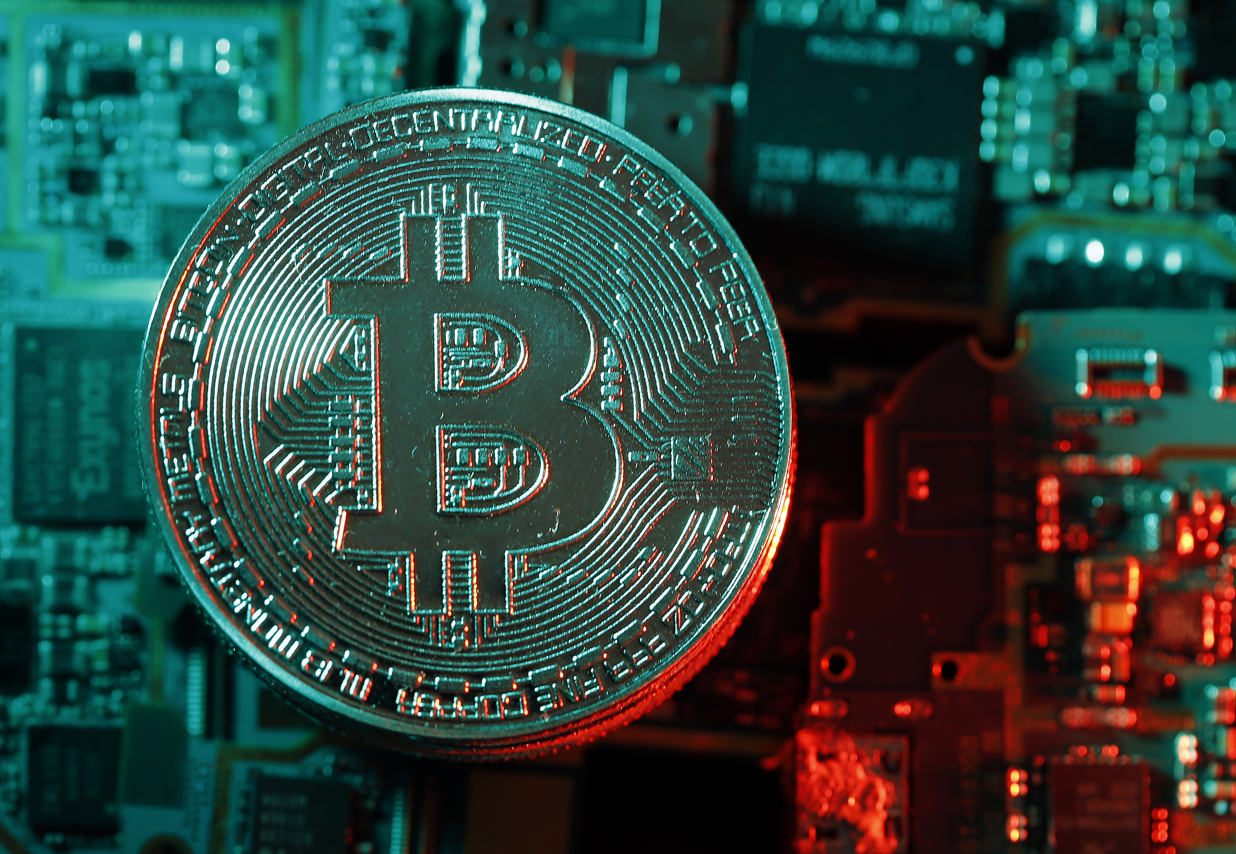 A blue and red photo with a physical coin bearing the logo of the digital cryptocurrency Bitcoin.