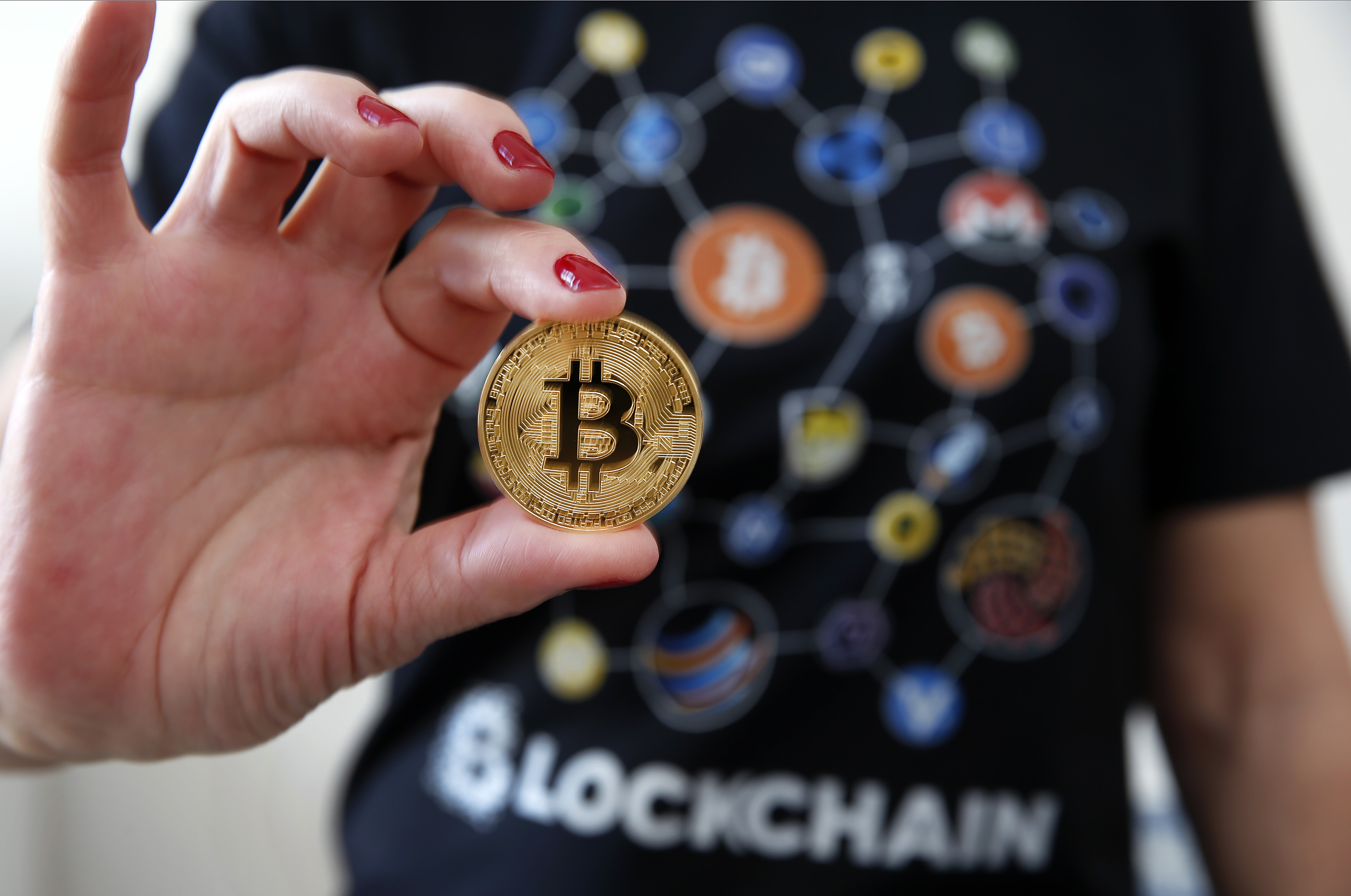 A woman dressed in a t-shirt with cryptocurrency logos holds a visual representation of the cryptocurrency Bitcoin on February 01, 2018 in Paris, France.