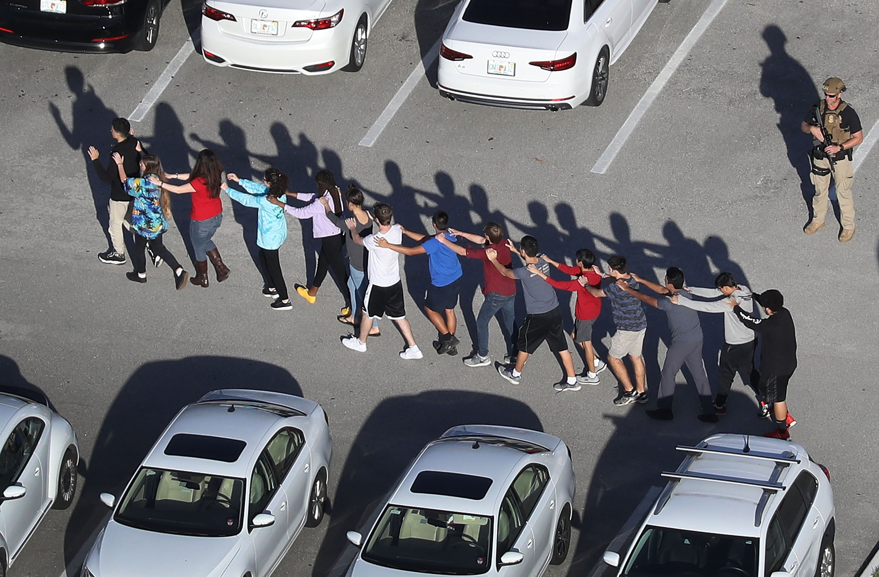 Students walk out of Marjory Stoneman Douglas High School in Parkland Florida after a shooting there. America is now debating arming teachers and gun control.