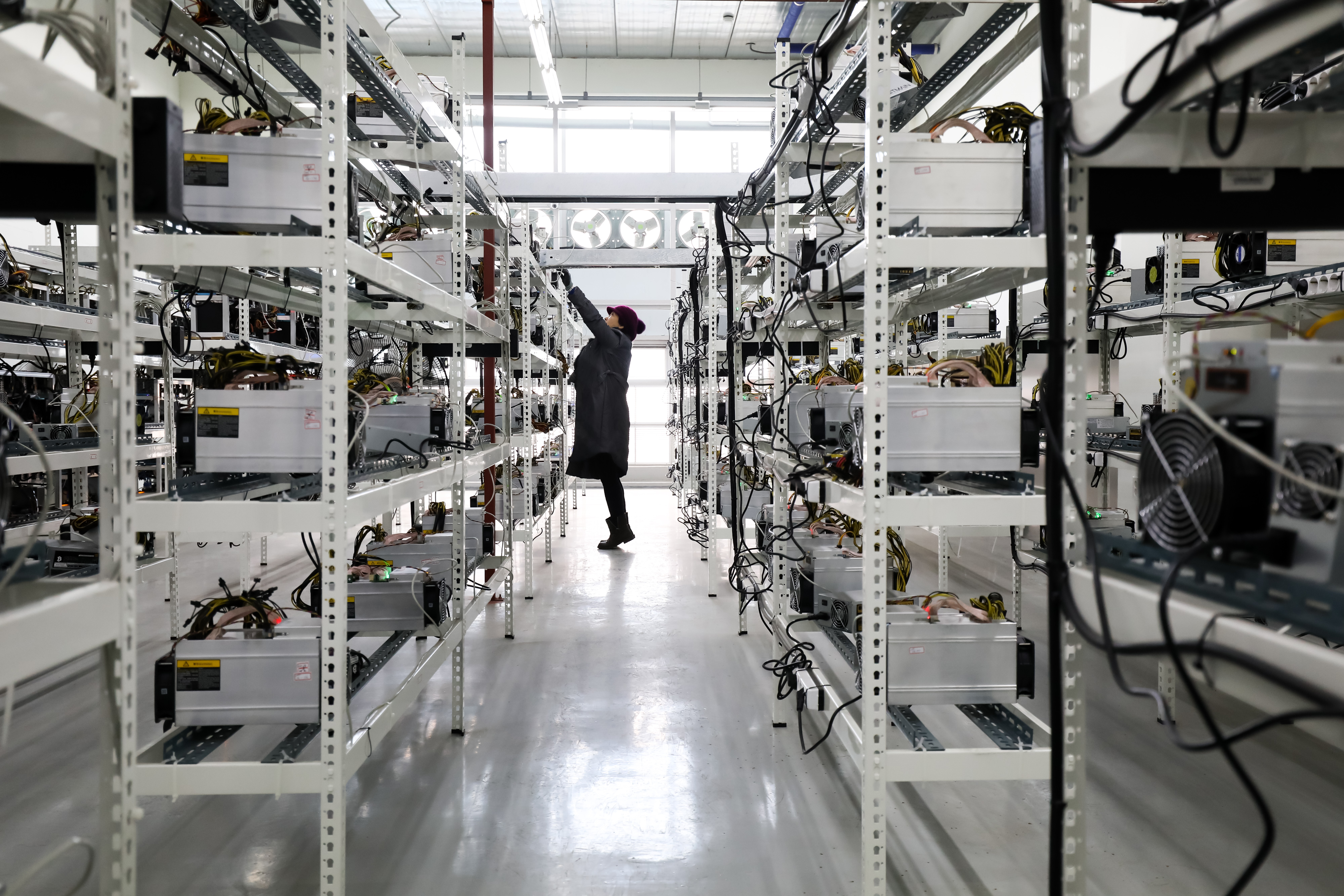 Woman inspects application-specific integrated circuit (ASIC) devices and power units, manufactured by Bitmain Technologies Inc., at her cryptocurrency mining facility