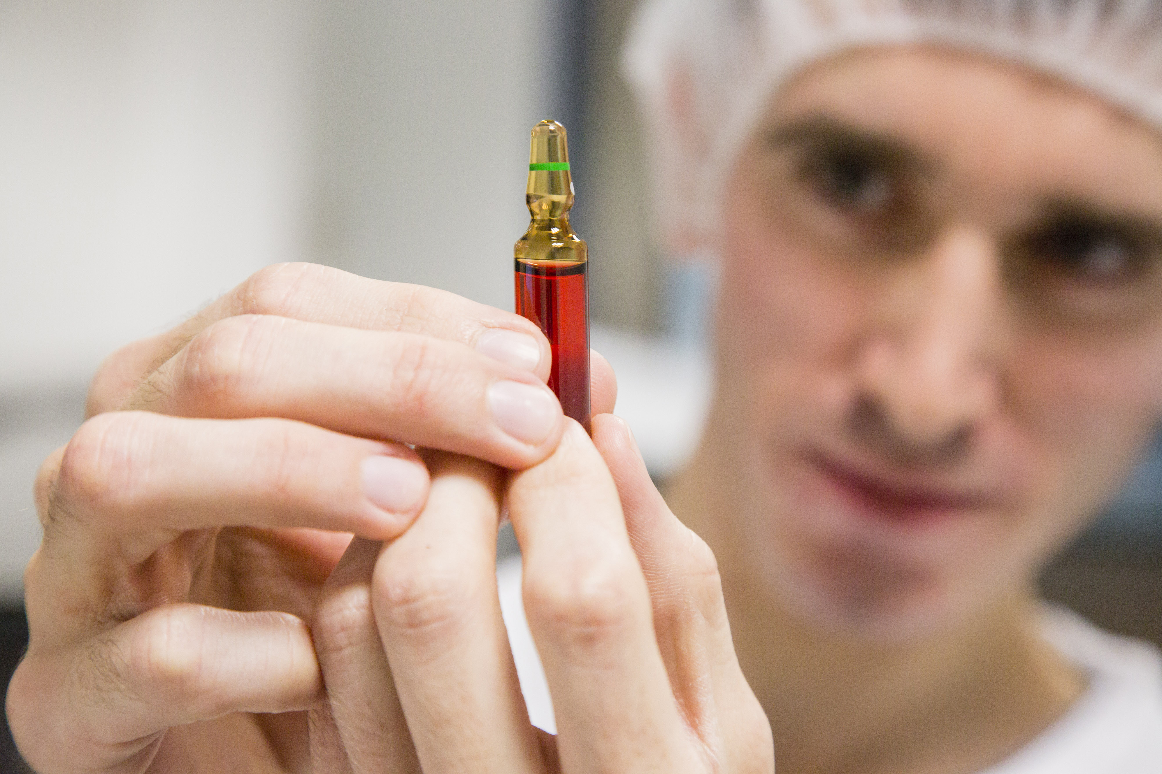 An employee inspects an ampoule of Neurobion vitamin supplement inside Merck KGaA's pharmaceutical laboratories