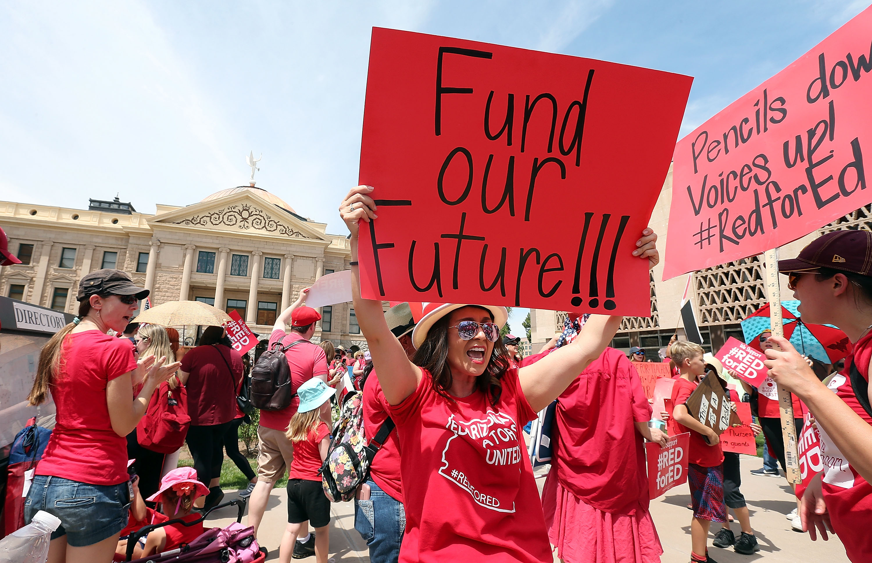 An Arizona teacher holds up a sign in front of the State Capitol during a rally on April 26, 2018 in Phoenix, Arizona.