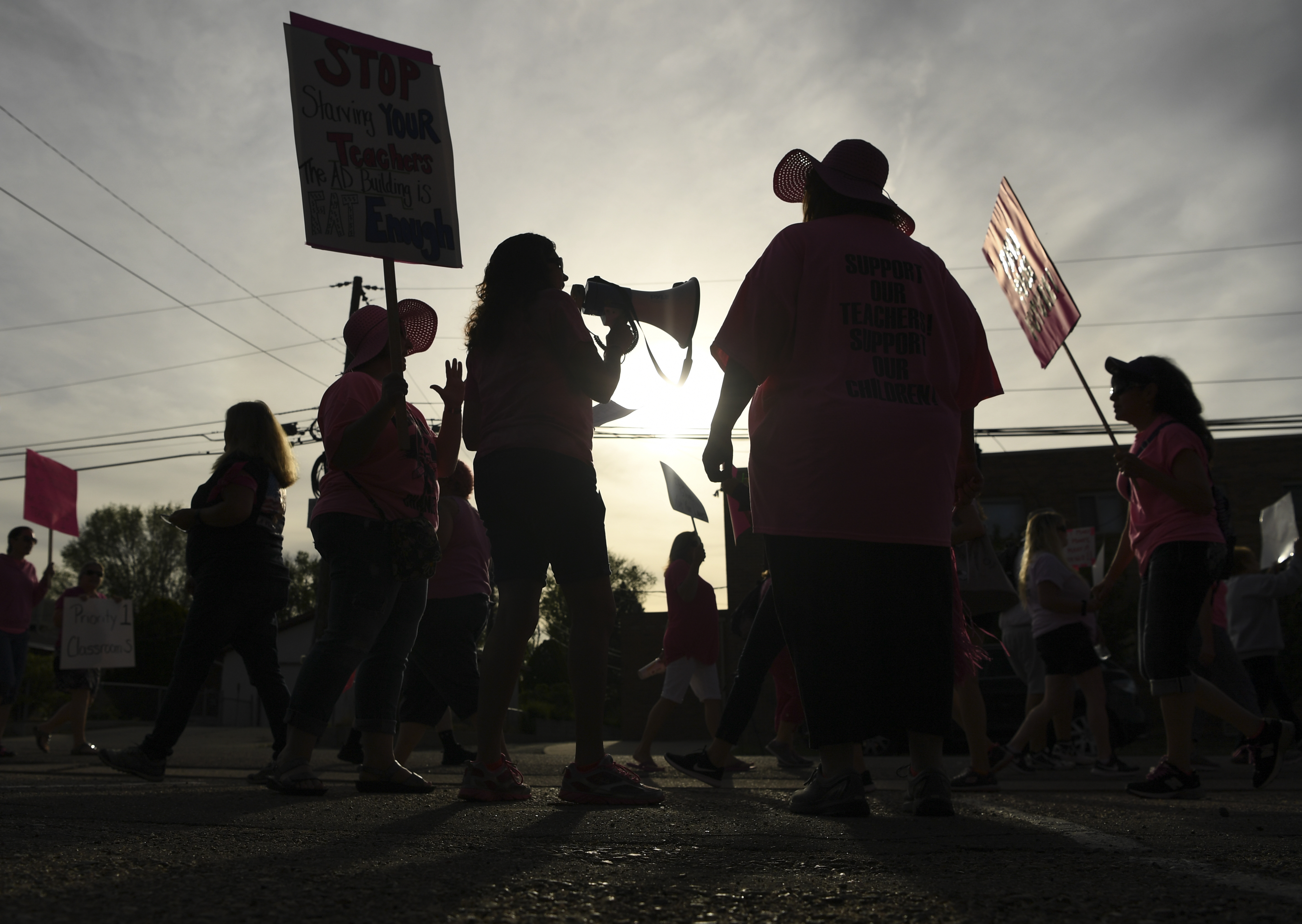 Teachers hold signs and a megaphone as they strike for higher wages in Colorado