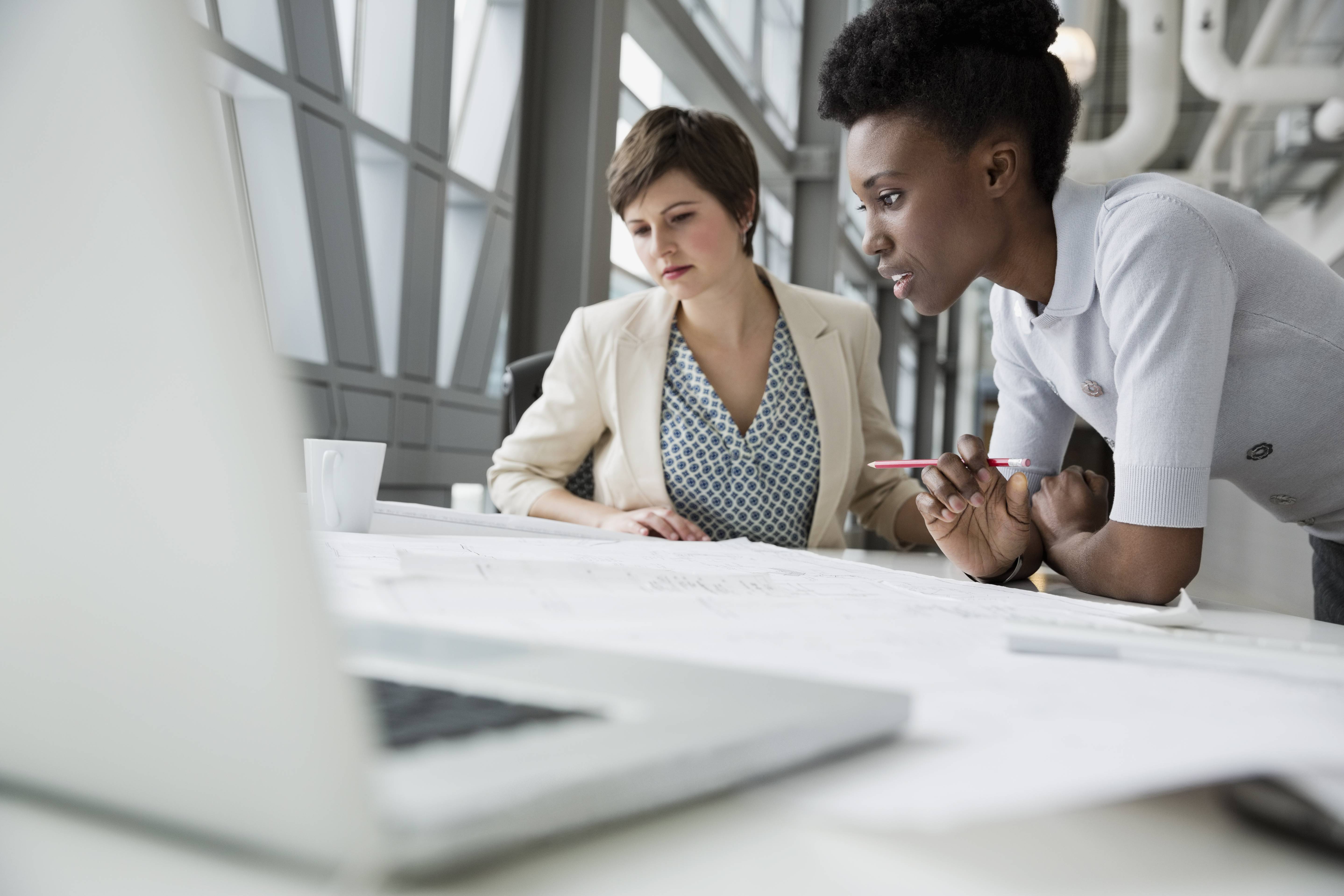 Businesswomen looking at blueprint in office building