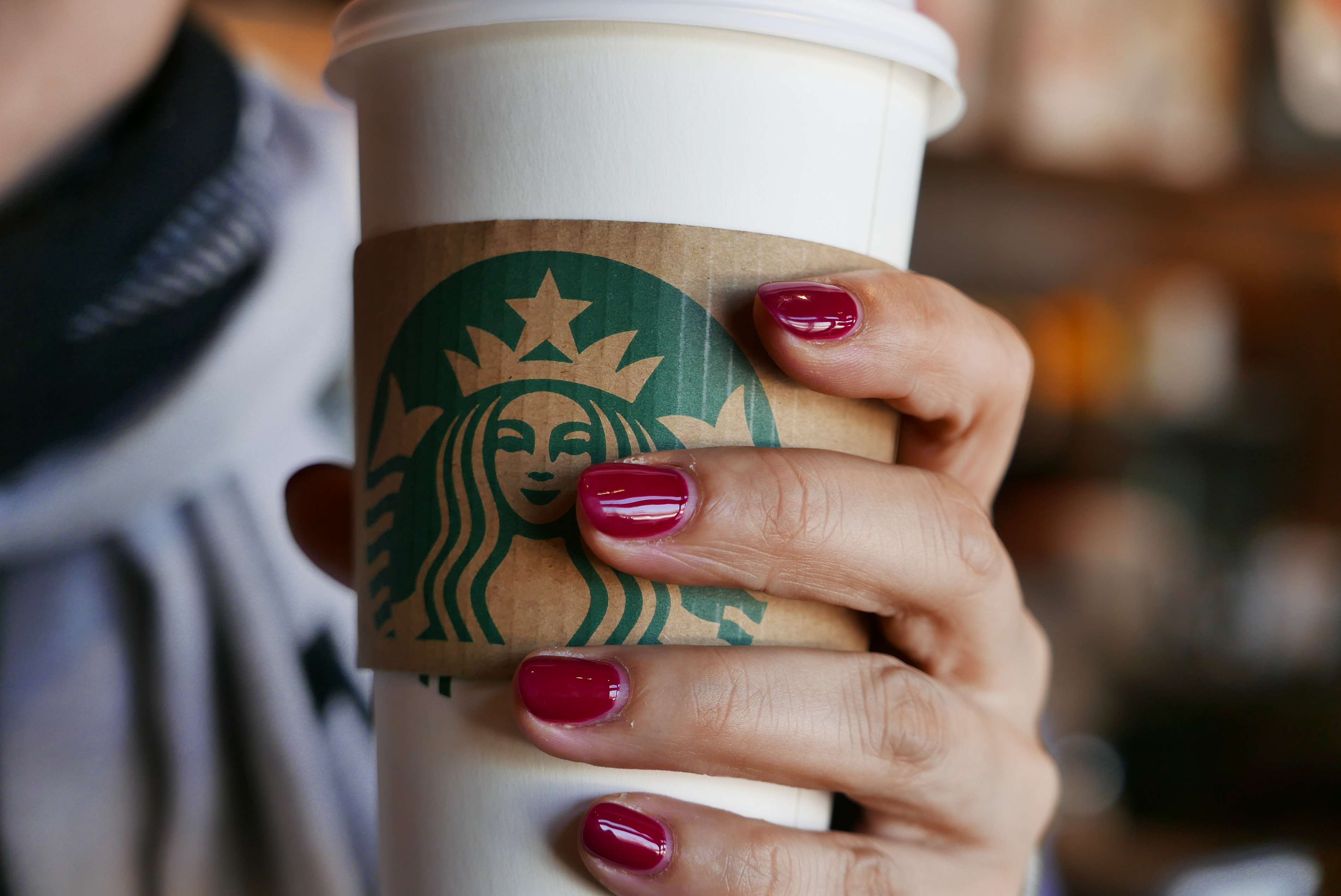 Hand holding a coffee cup in a Starbucks coffee shop. In