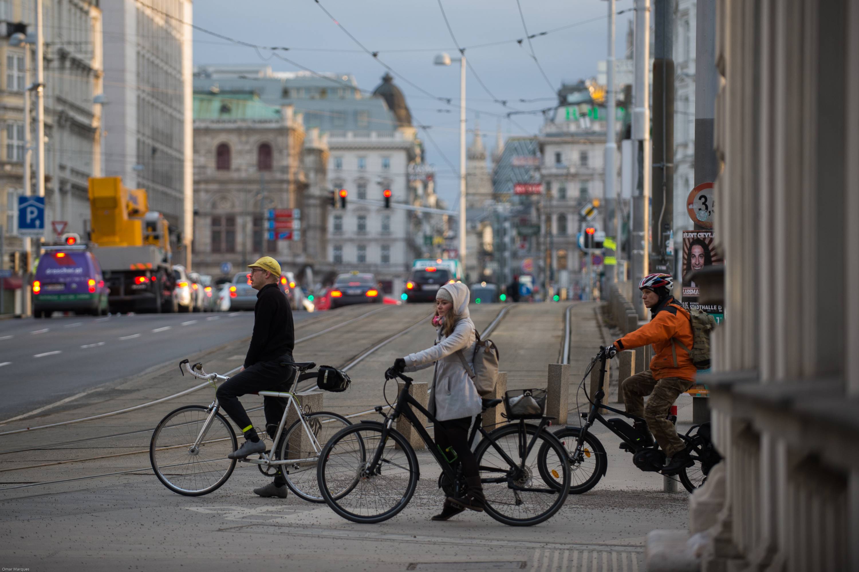 People seen on bicycles as they wait to cross the road in