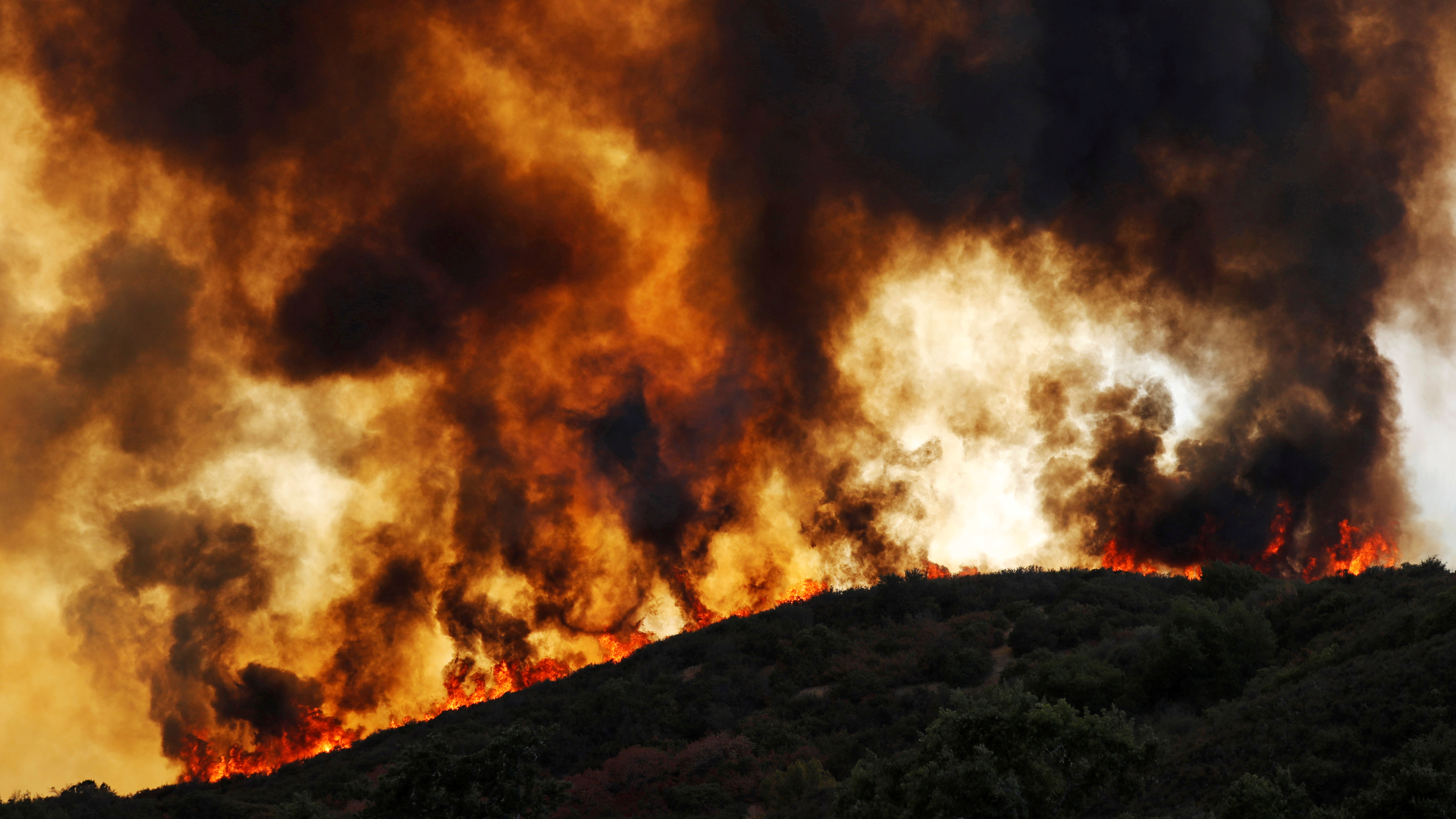 Wind-driven flames roll over a hill towards homes during the River Fire in Lakeport, California