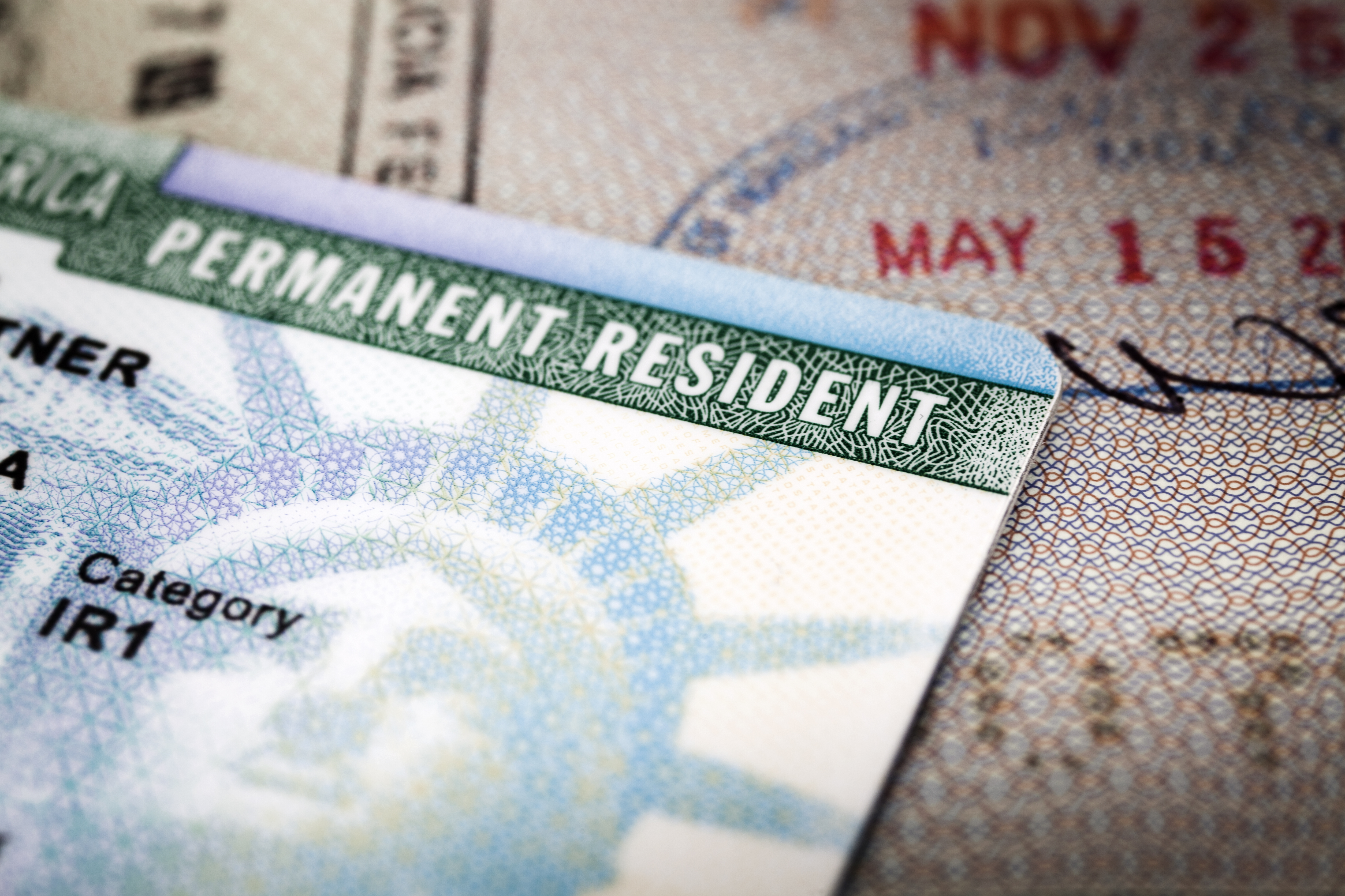 A green card lying on top of a passport