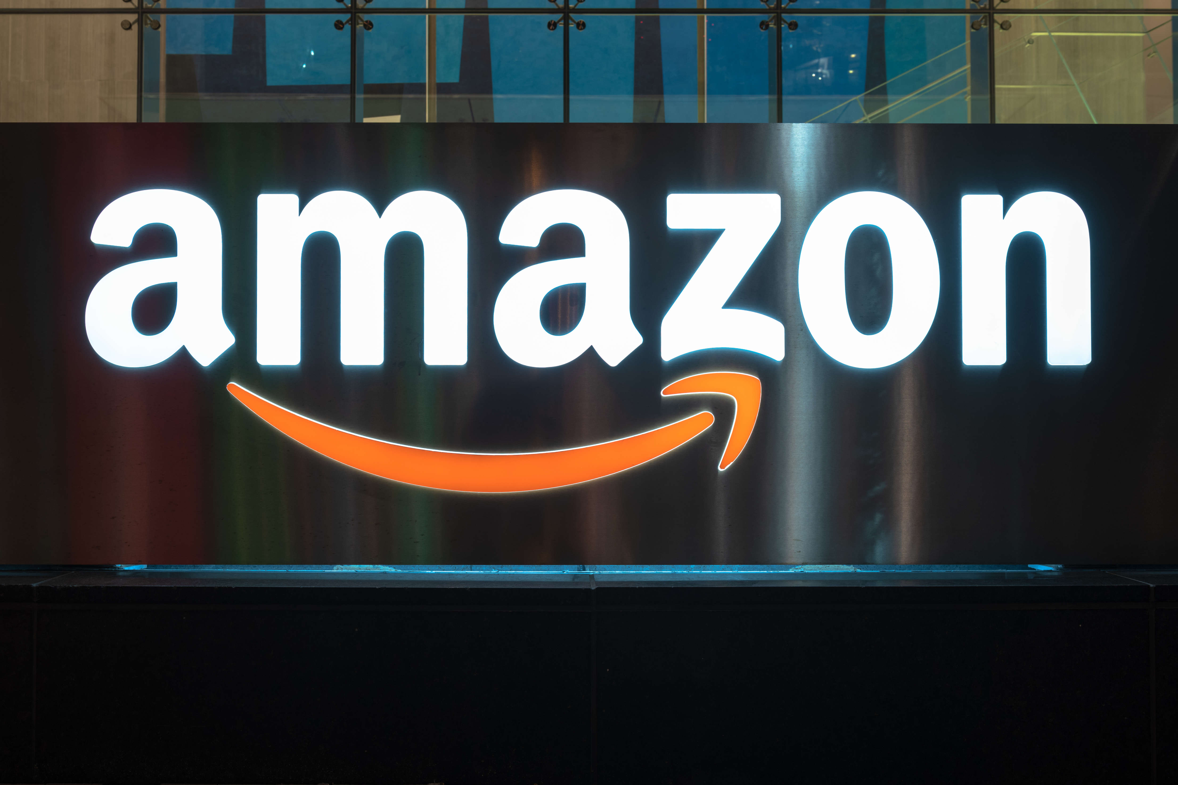 The Amazon logo illuminated at night. The sign can be seen