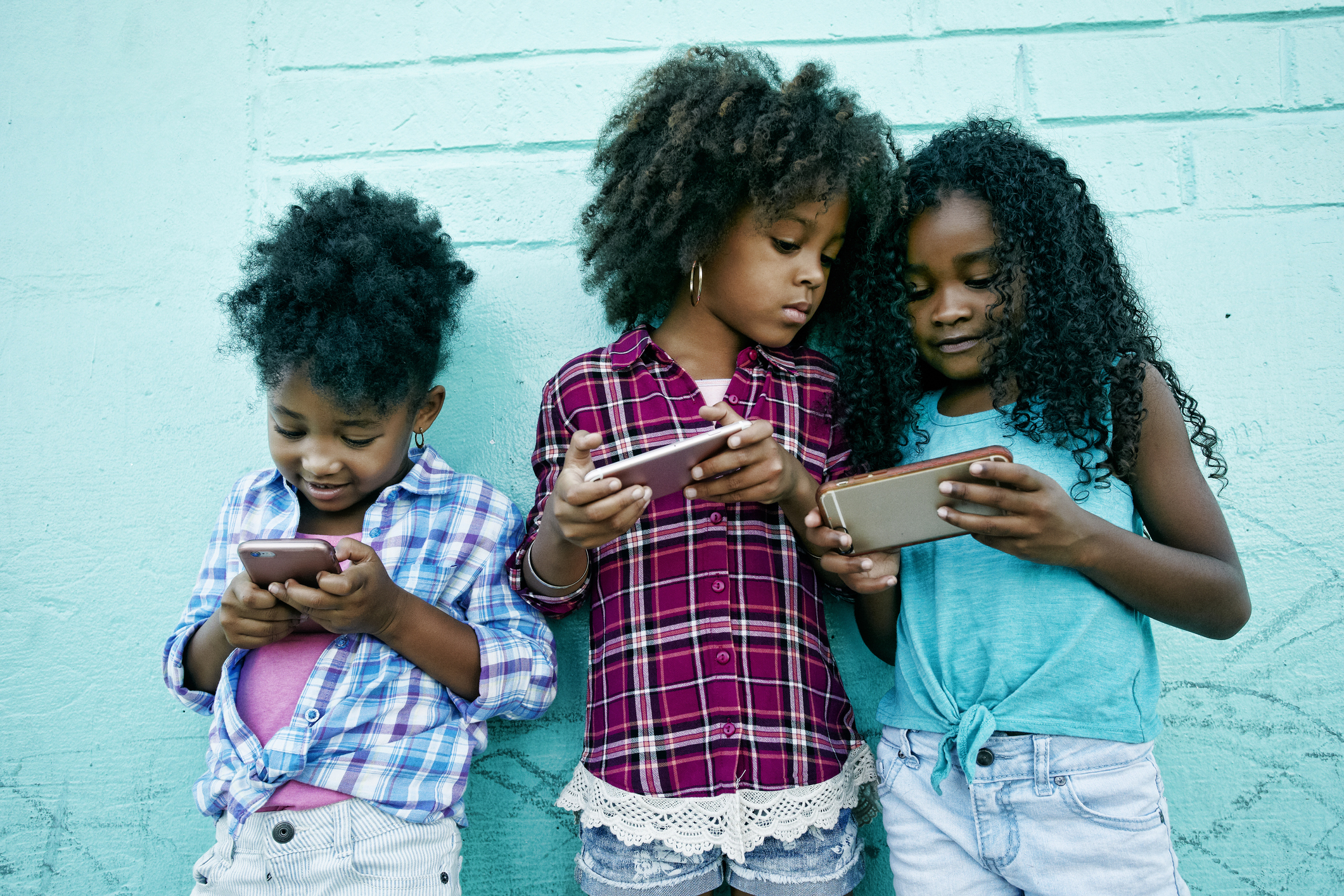 Girls leaning on wall texting on cell phones