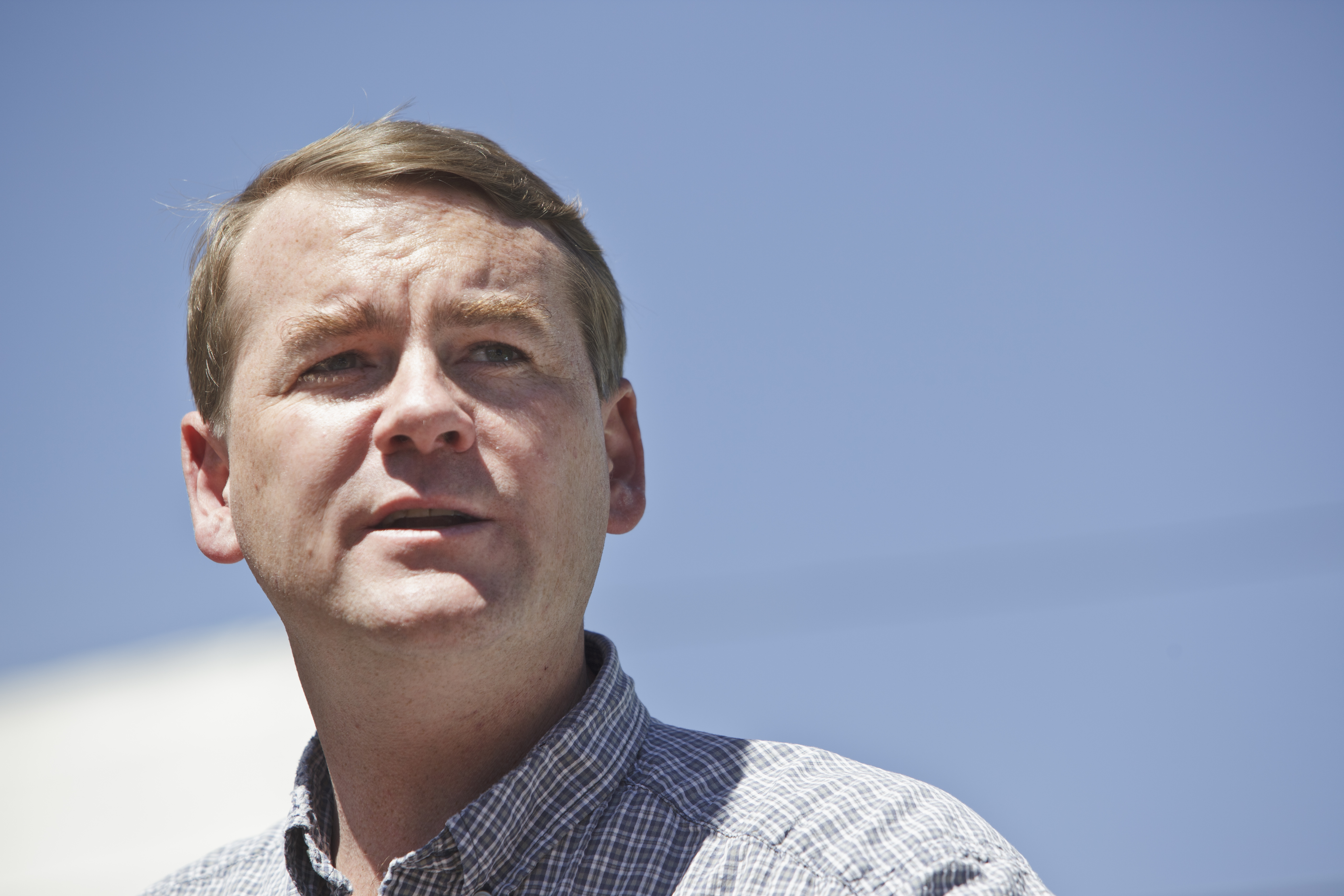 Sen. Michael Bennet stands against a sky backdrop.