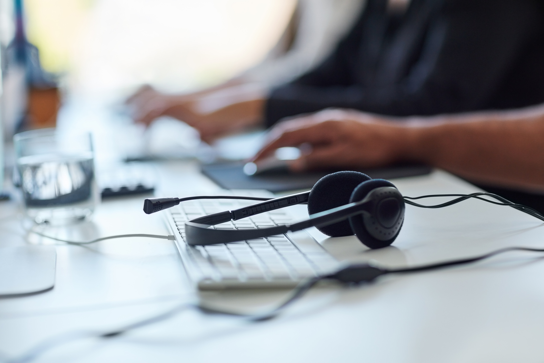 Shot of a set of headsets lying on a desk with workers sitting in the background

PeopleImages—Getty Images