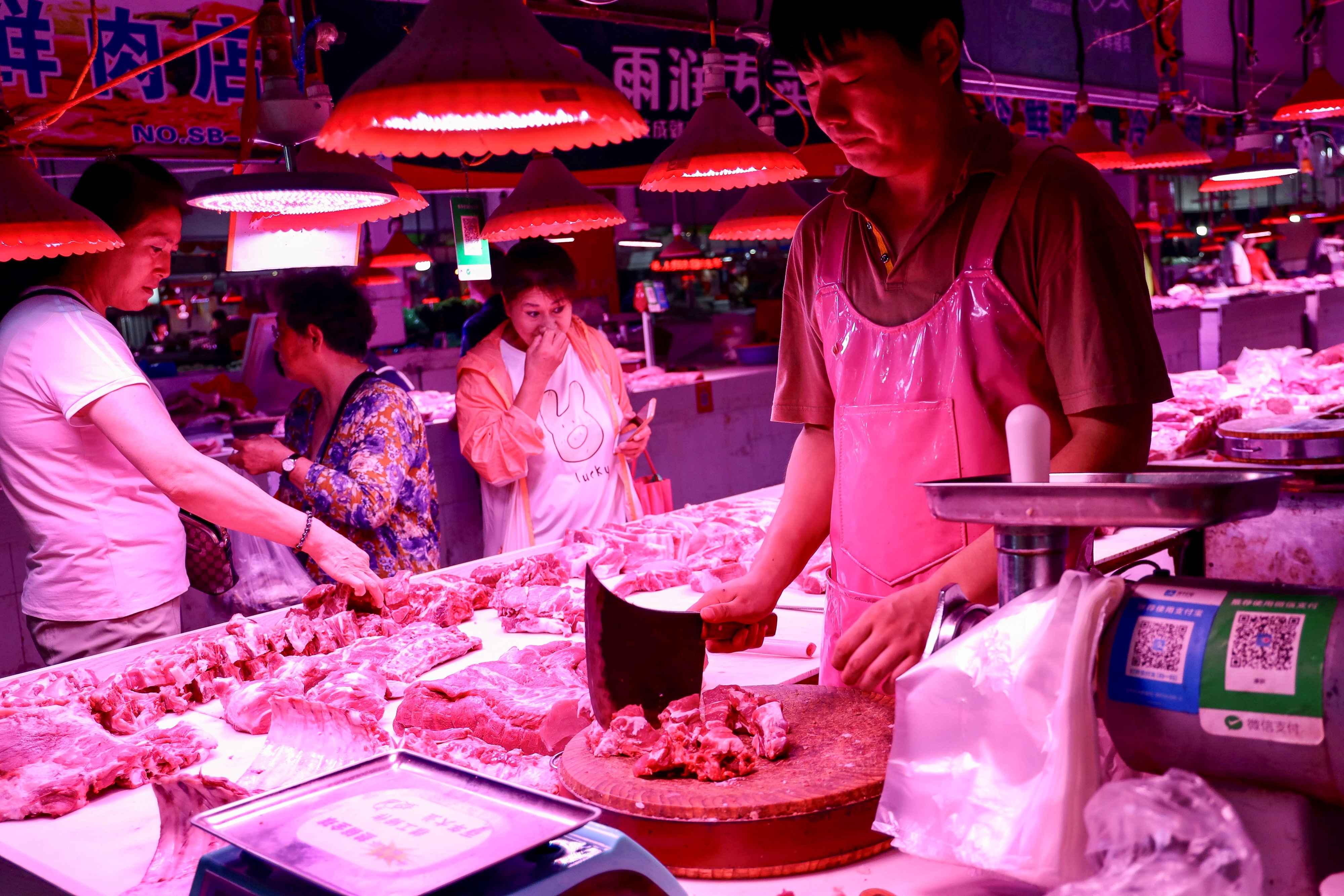 A butcher (R) chops pork meat at a market in Beijing on September 5, 2019. (Photo by STR / AFP) / China OUT (Photo credit should read STR/AFP/Getty Images)