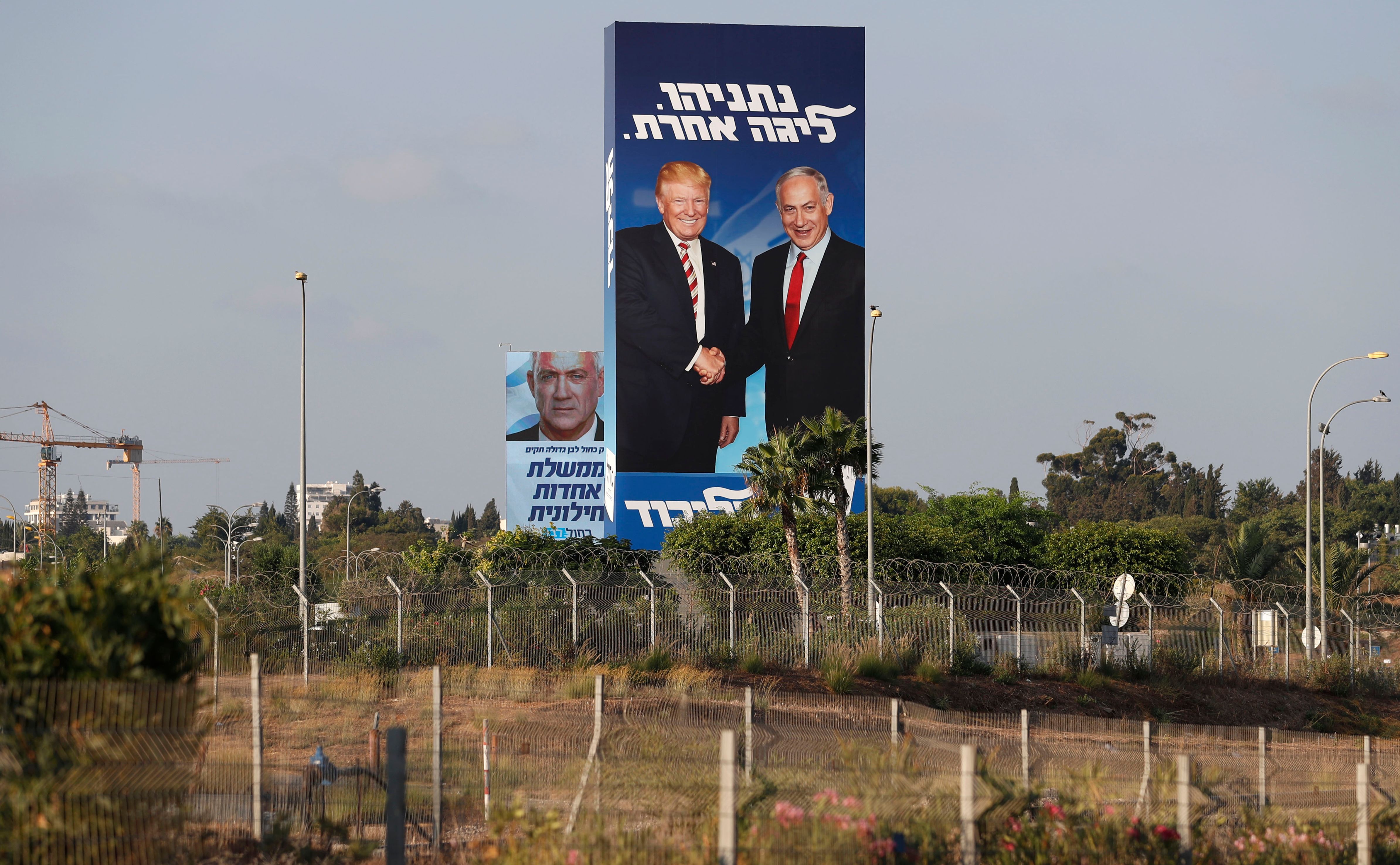 This picture taken on September 9, 2019 shows Israeli election billboards in the Israeli coastal city of Tel Aviv (R to L) for the Likud party showing US President Donald Trump shaking hands with Likud chairman and Prime Minister Benjamin Netanyahu with a caption in Hebrew reading "Netanyahu, in another league"; and another for the "Blue and White" (Kahol Lavan) electoral alliance showing the face of retired general Benny Gantz and a caption in Hebrew reading "only with the Blue and White will create a united secular government".