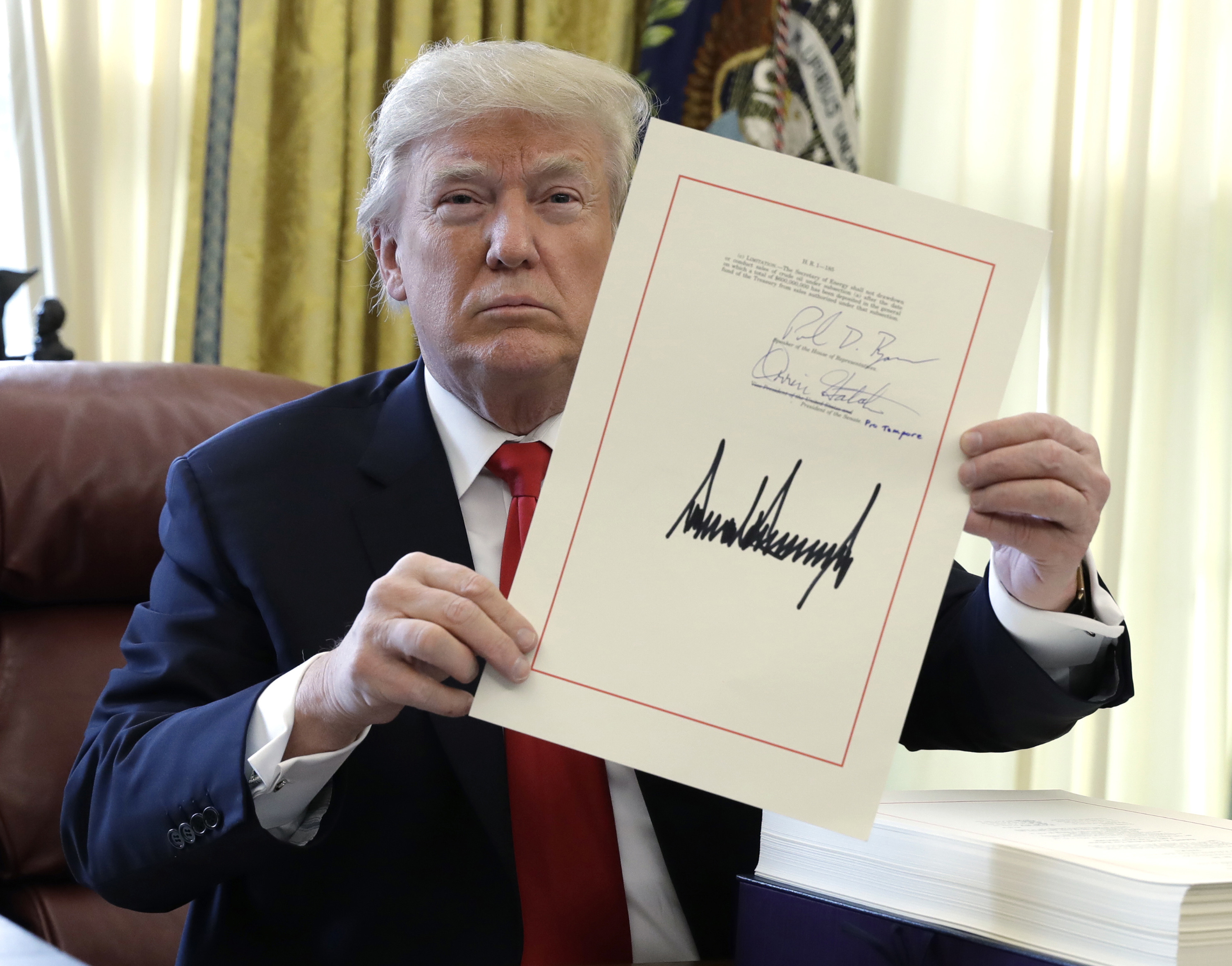 Donal Trump holding his signed tax reform bill
