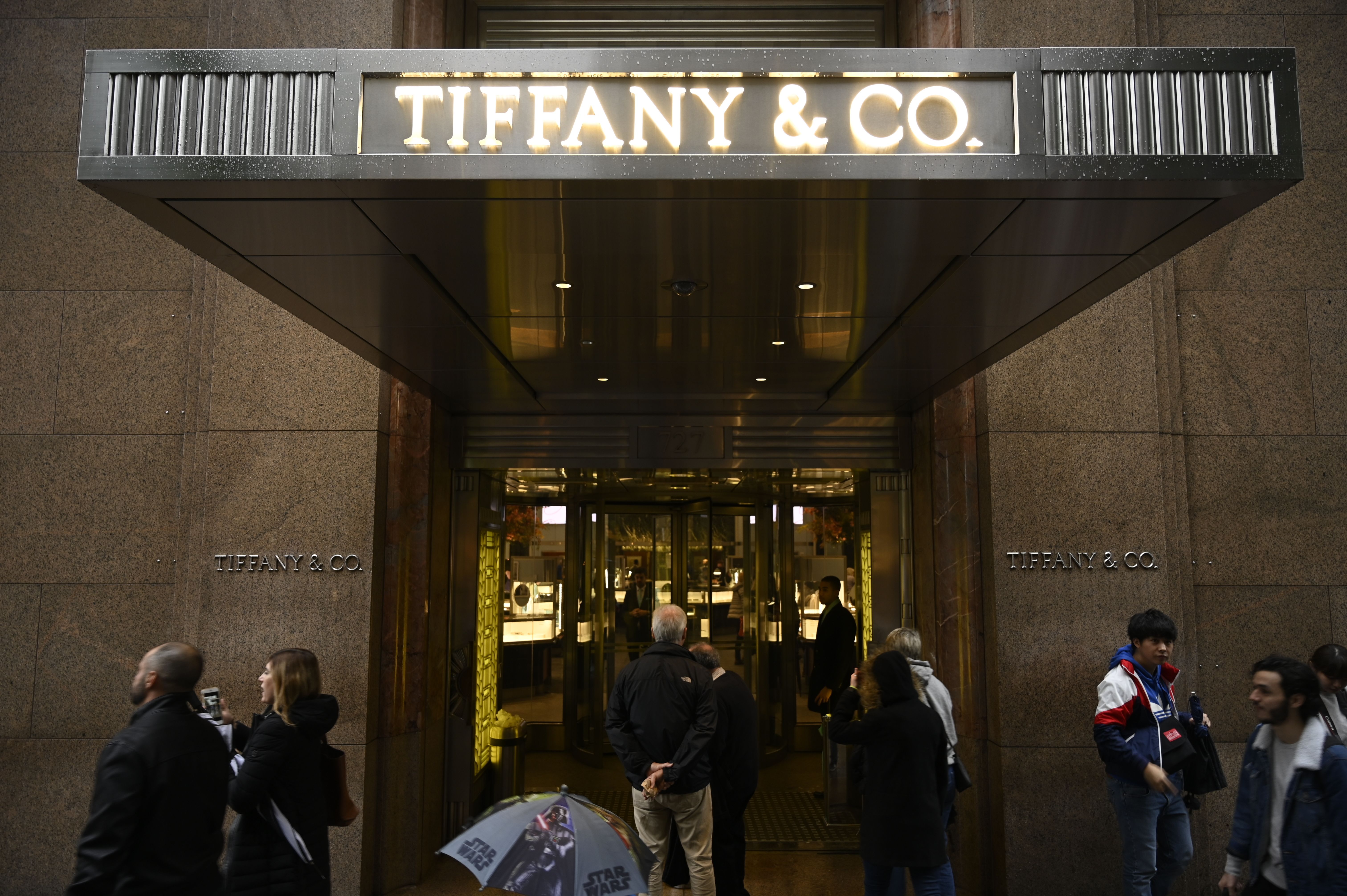 People walk past the headquarters of luxury jewelry and specialty retailer Tiffany & Co on 5th Avenue in Manhattan on October 27, 2019 in New York City. - LVMH, the French owner of Louis Vuitton, is exploring a takeover of Tiffany & Co to expand in the US jewelry market, according to reports. (Photo by Johannes EISELE / AFP) (Photo by JOHANNES EISELE/AFP via Getty Images)