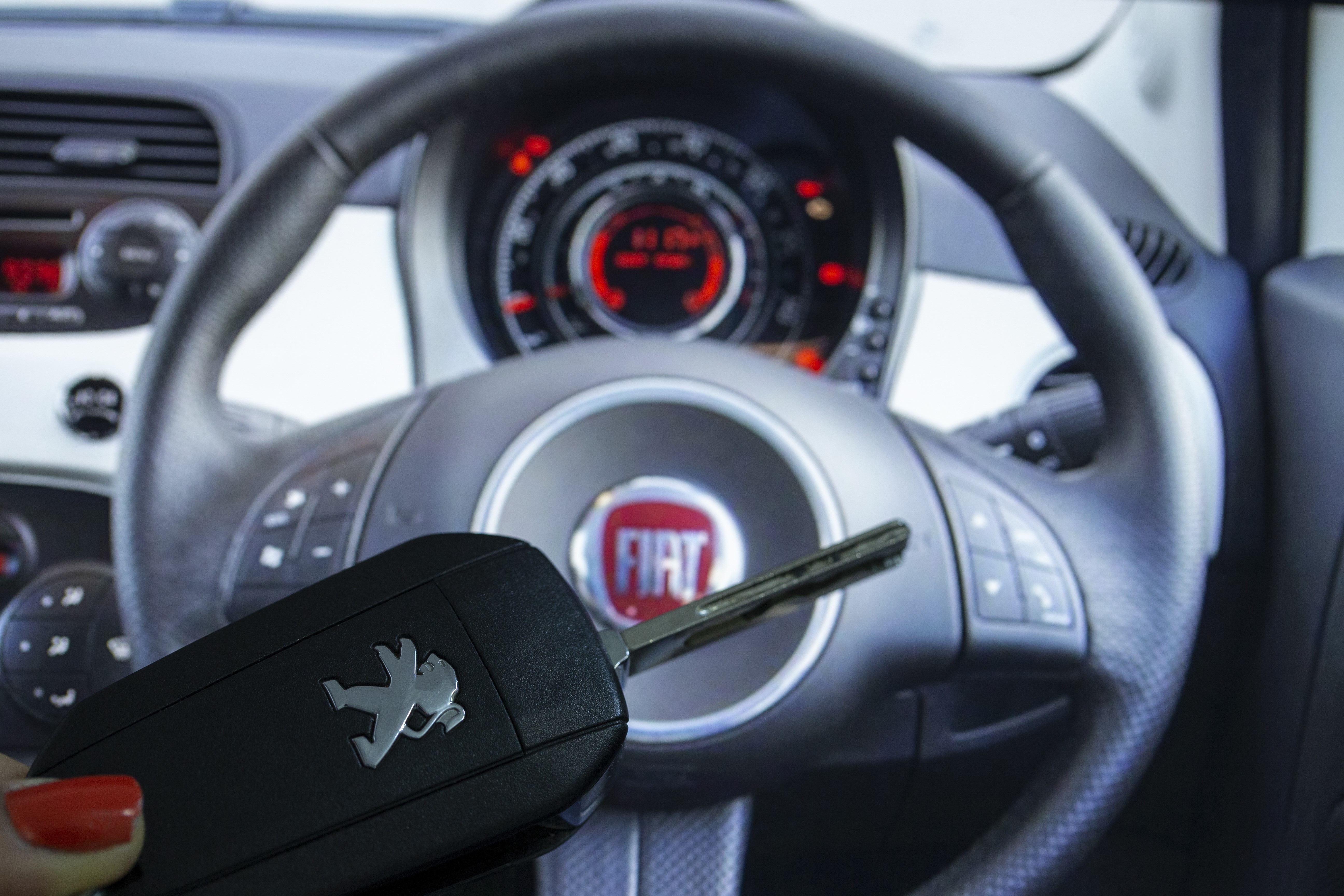 ANKARA, TURKEY - NOVEMBER 26: A woman holds a Peugeot car key as Fiat logo is seen behind in Ankara, Turkey on November 26, 2019. (Photo by Aytac Unal/Anadolu Agency/Getty Images)