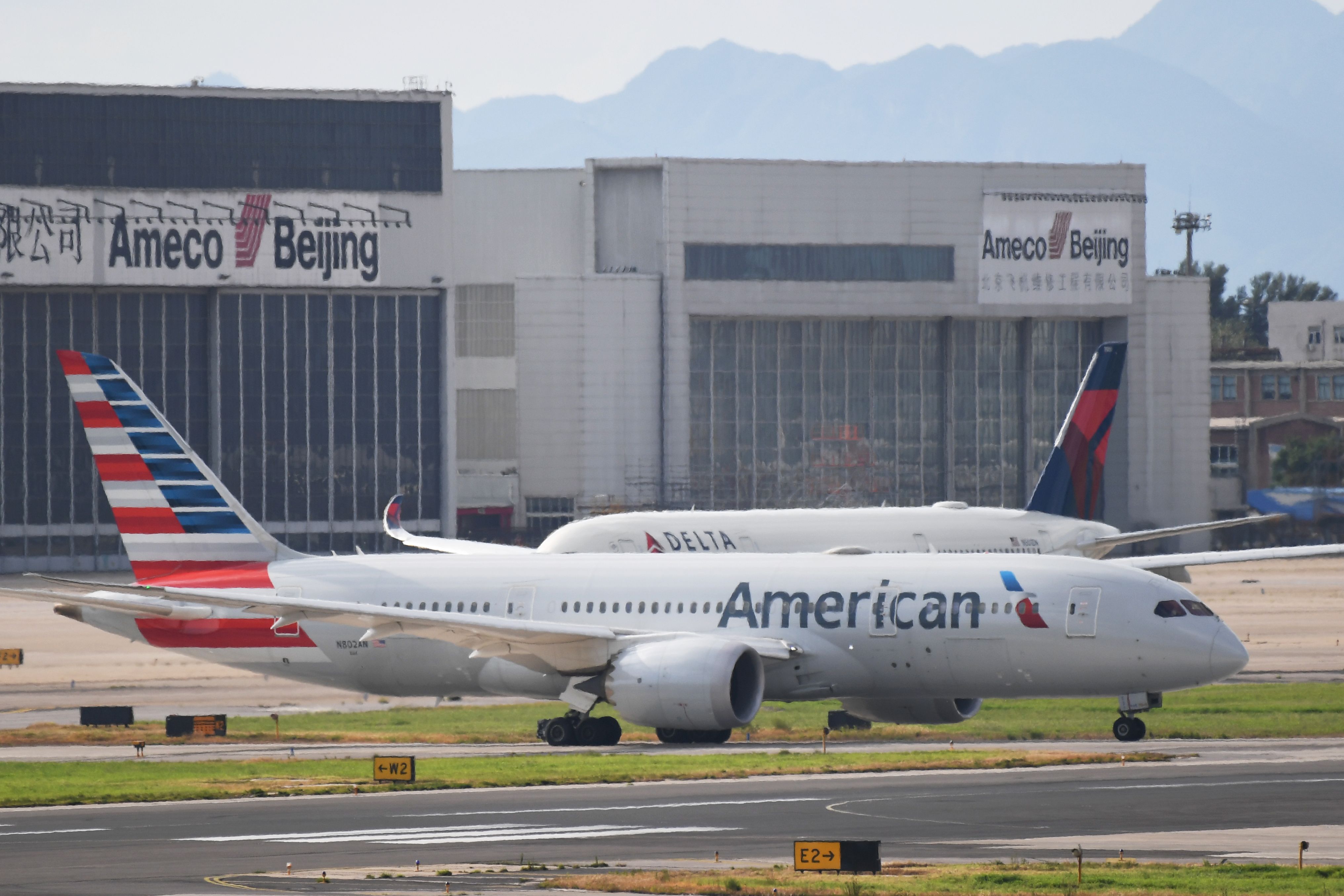 An American Airlines Boeing 787 (front) and Delta Airlines Airbus A350 aircraft (background, obscured) wait to take off at Beijing airport on July 25, 2018. - Beijing hailed "positive steps" as major US airlines and Hong Kong's flag carrier moved to comply on July 25 with its demand to list Taiwan as part of China, sparking anger on the island. (Photo by GREG BAKER / AFP) (Photo credit should read GREG BAKER/AFP via Getty Images)