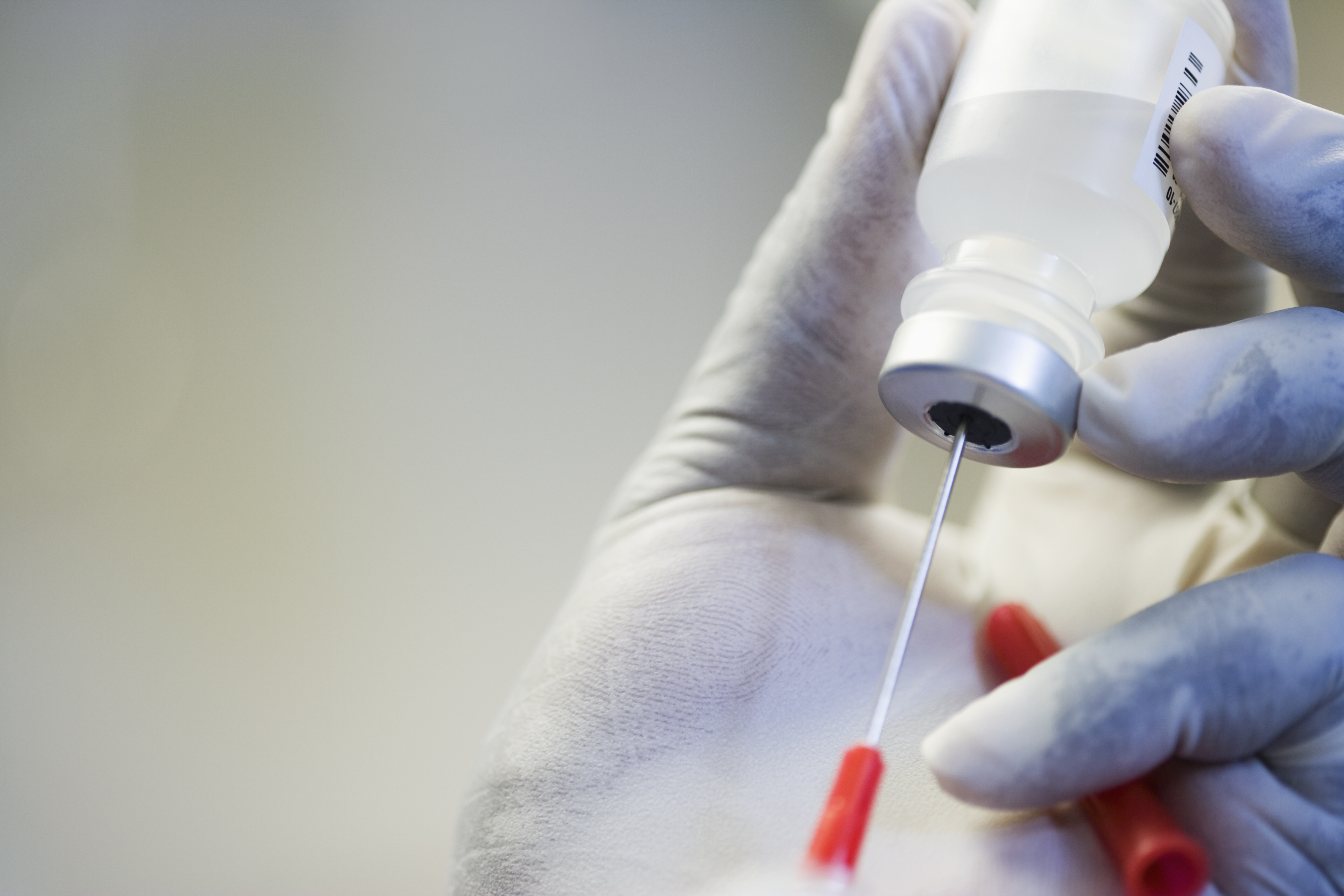 Close up of hand in rubber glove filling syringe