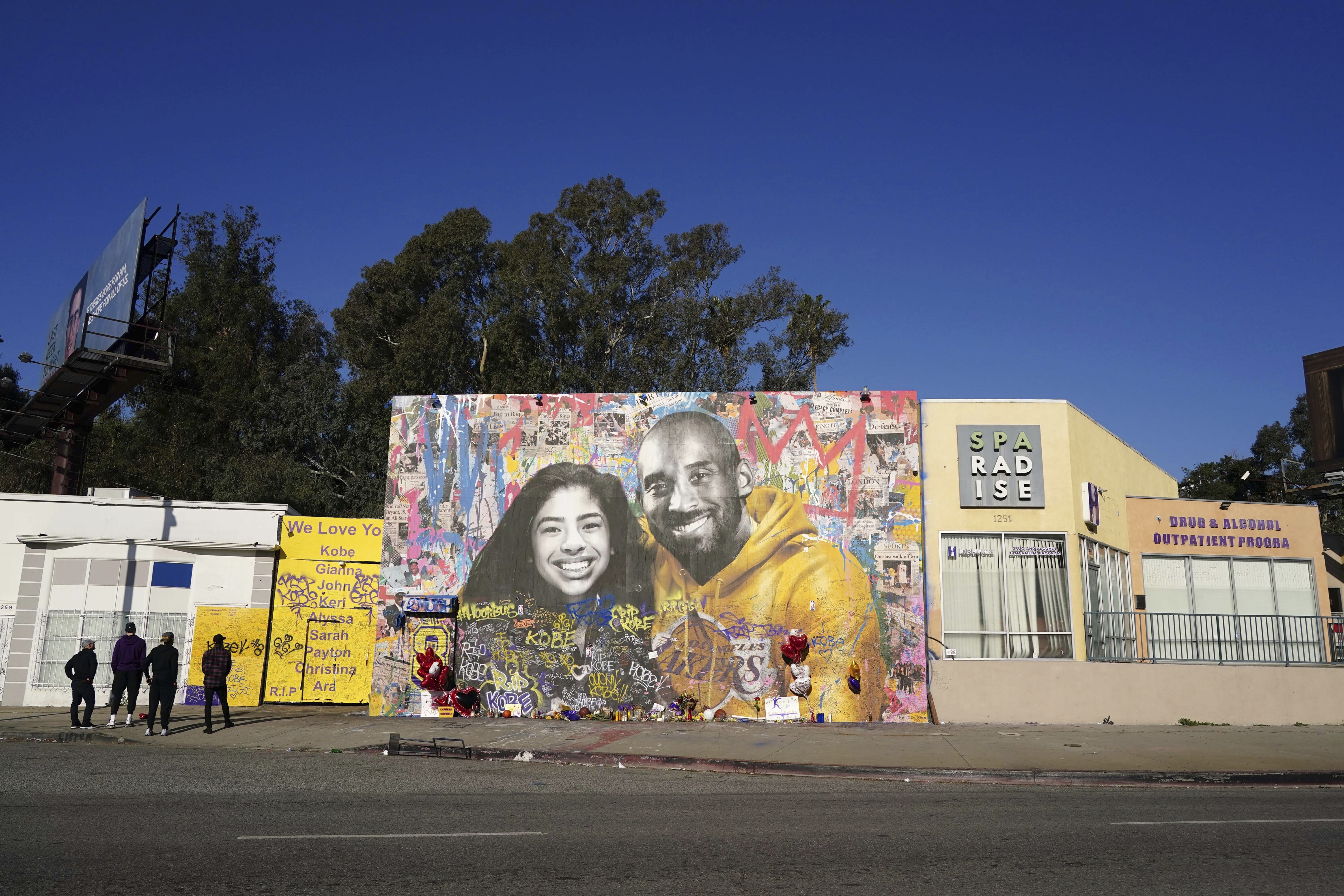 General overall view of Kobe Bryant memorial mural at Sparadise La Brea at 1251 St. La Brea Ave., Sunday, Feb 16, 2020, in Los Angeles. The mural, created street artist Thierry Guetta aka Mr. Brainwash, showcases Bryant and his daughter Gigi Bryant (Gianna Bryant), with the former basketball player wearing a Lakers sweatshirt against a colorful background and newspaper images of Bryant during his NBA years, on the front. There is another image of Bryant in his purple Lakers uniform with a quote of his written next to him on the side of the building. This mural also pays tribute to the other seven people-pilot Ara Zobayan, Christina Mauser, Sarah Chester, Payton ChesterJohn Altobelli, Keri Altobelli and Alyssa Altobelli-who passed away in the helicopter crash in Calabasas, Calif. on Jan 26, 2020. (Kirby Lee via AP)
